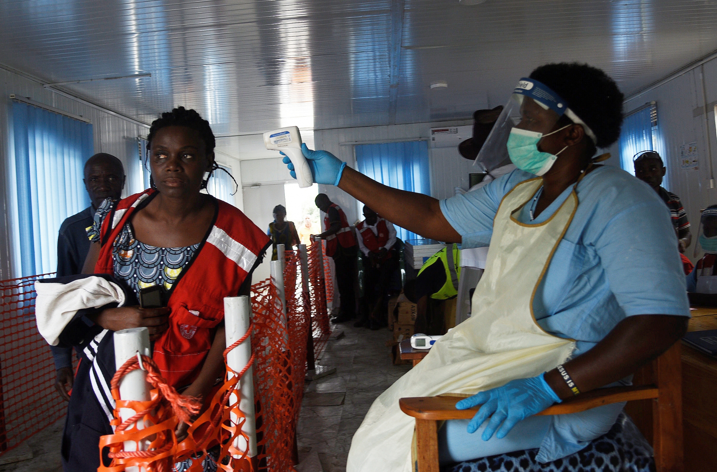 A woman passing through border check point gets temperature screening from health official.