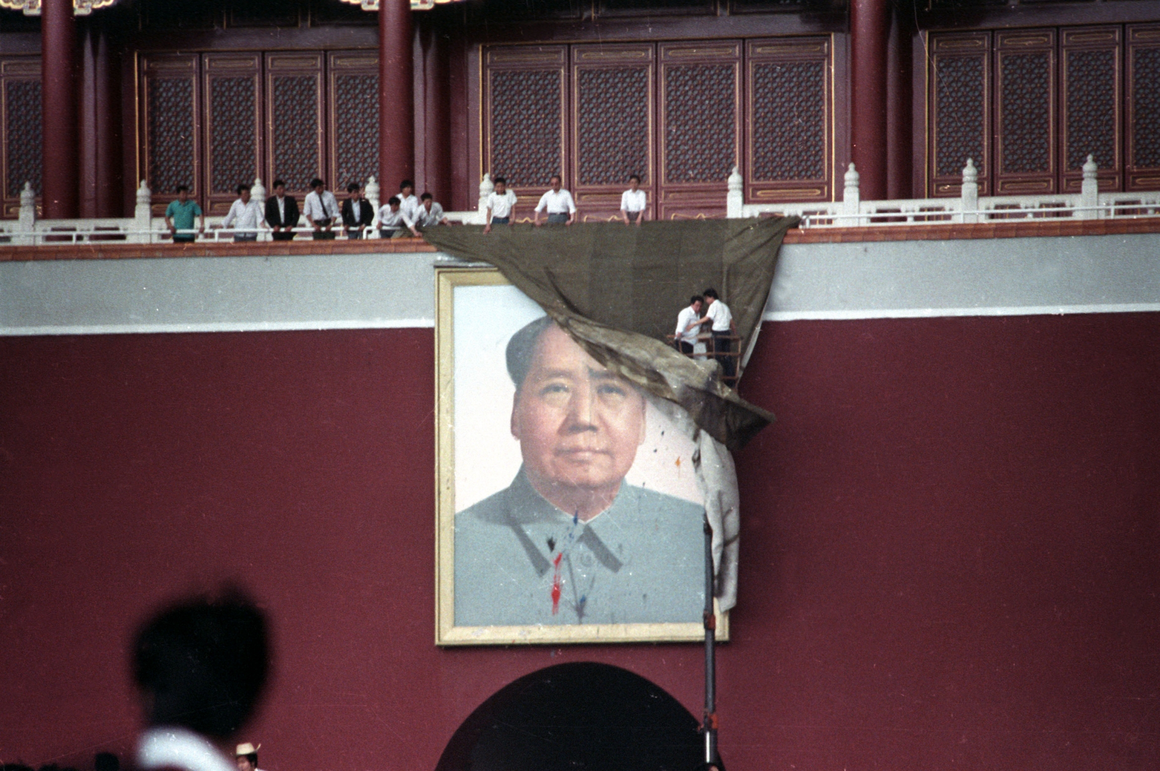 Workmen try to cover the portrait of Mao Zedong in Beijing's Tiananmen Square after it was pelted with paint on May 23, 1989. A portrait of Chairman Mao is covered.