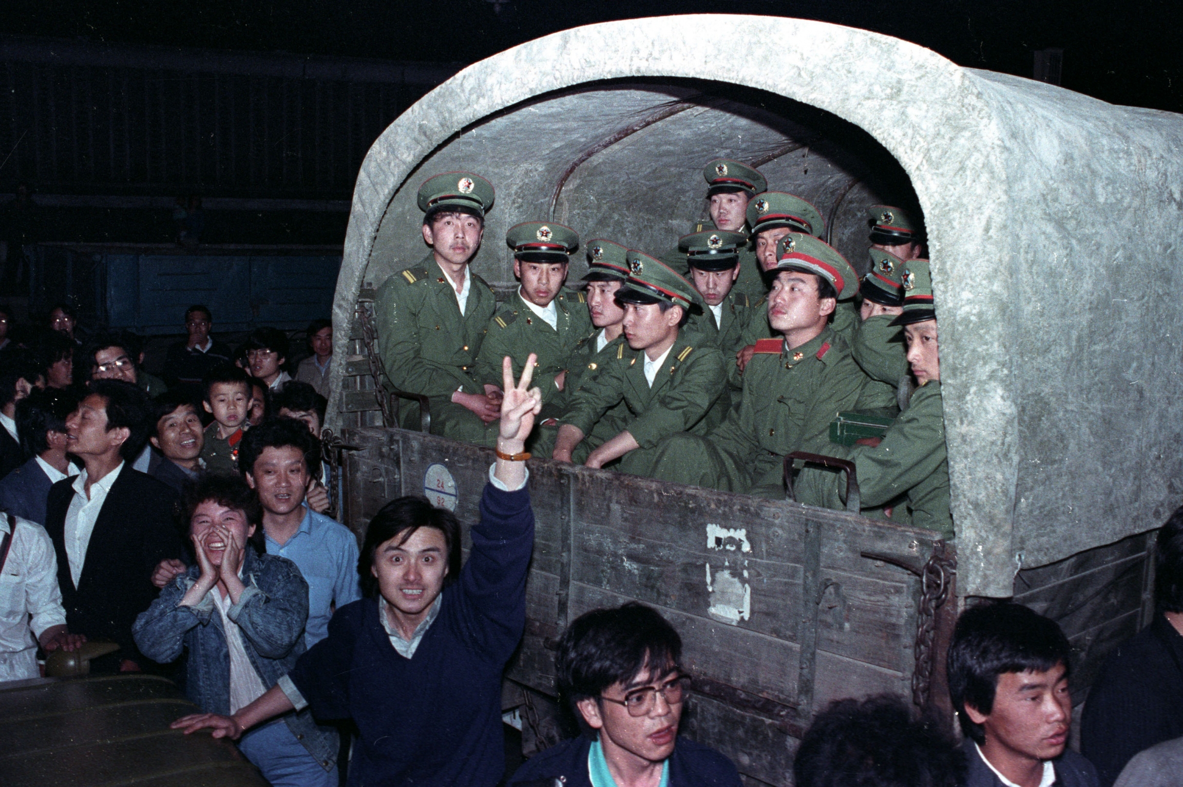 Residents of Beijing surround an army convoy of 4,000 soldiers on May 20, 1989, in a suburb of the city. At night a group of students surround a military vehicle.
