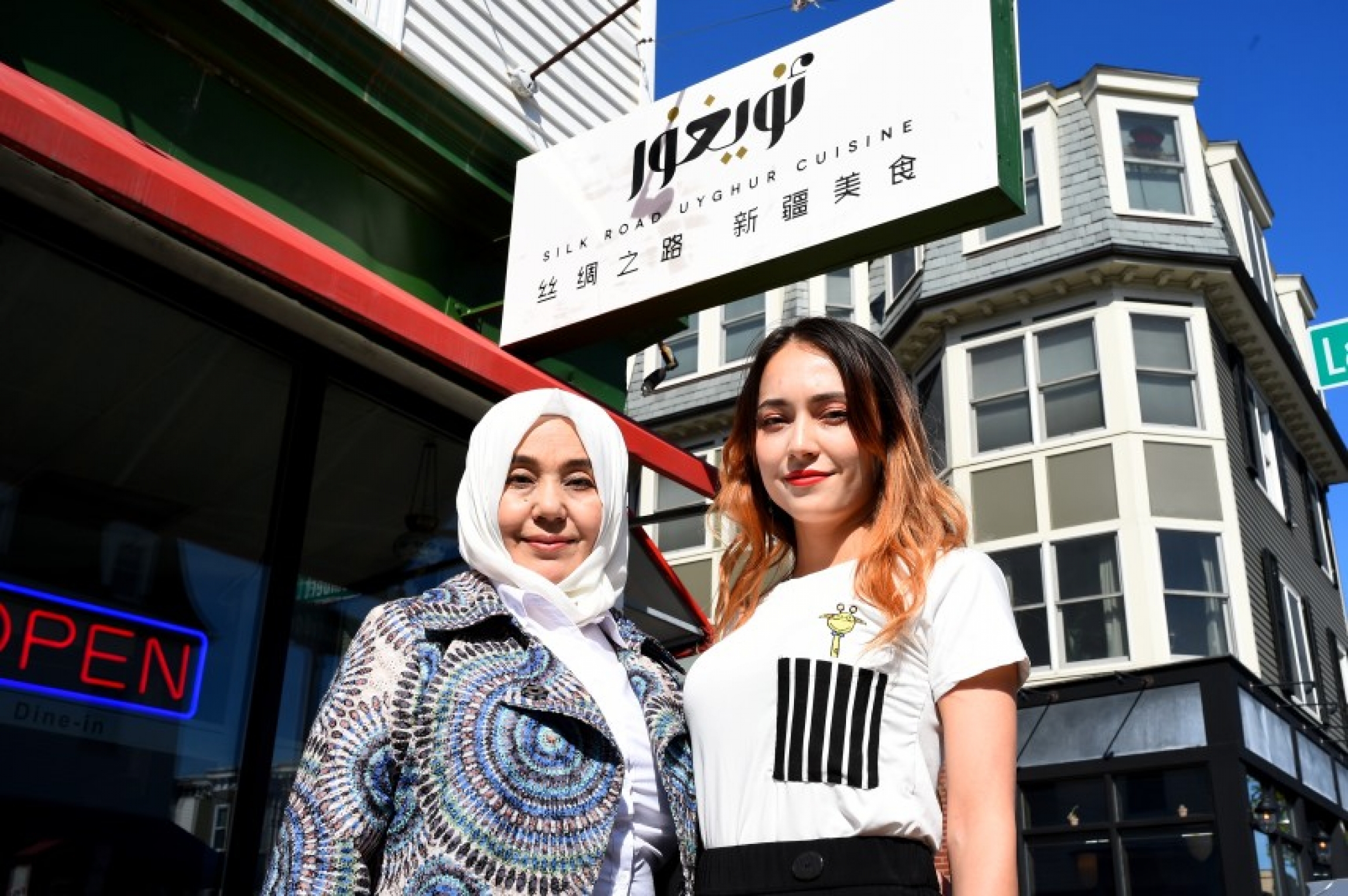 Adila Sadir, co-owner of Silk Road Restaurant in Cambridge, the only Uighur restaurant in Massachusetts, stands outside her restaurant with her mother, Maria Mohammad, who works as a chef in the restaurant. Two women stand outside a restaurant
