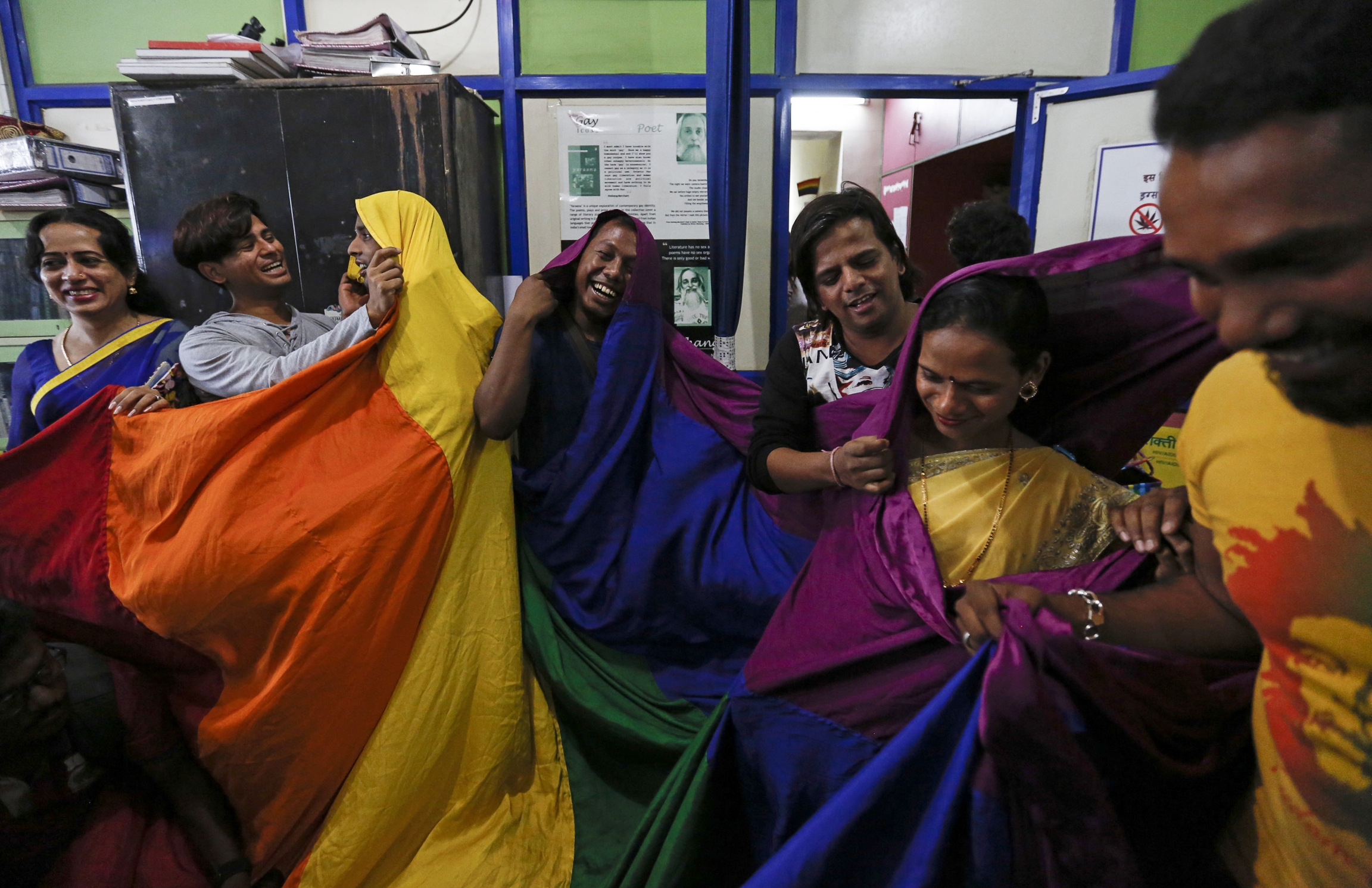 LGBTQ rights activists cover themselves with a rainbow flag as they celebrate the Supreme court's decision on gay sex in Mumbai. Gay rights activists in India celebrate and cover themselves in rainbow flags.