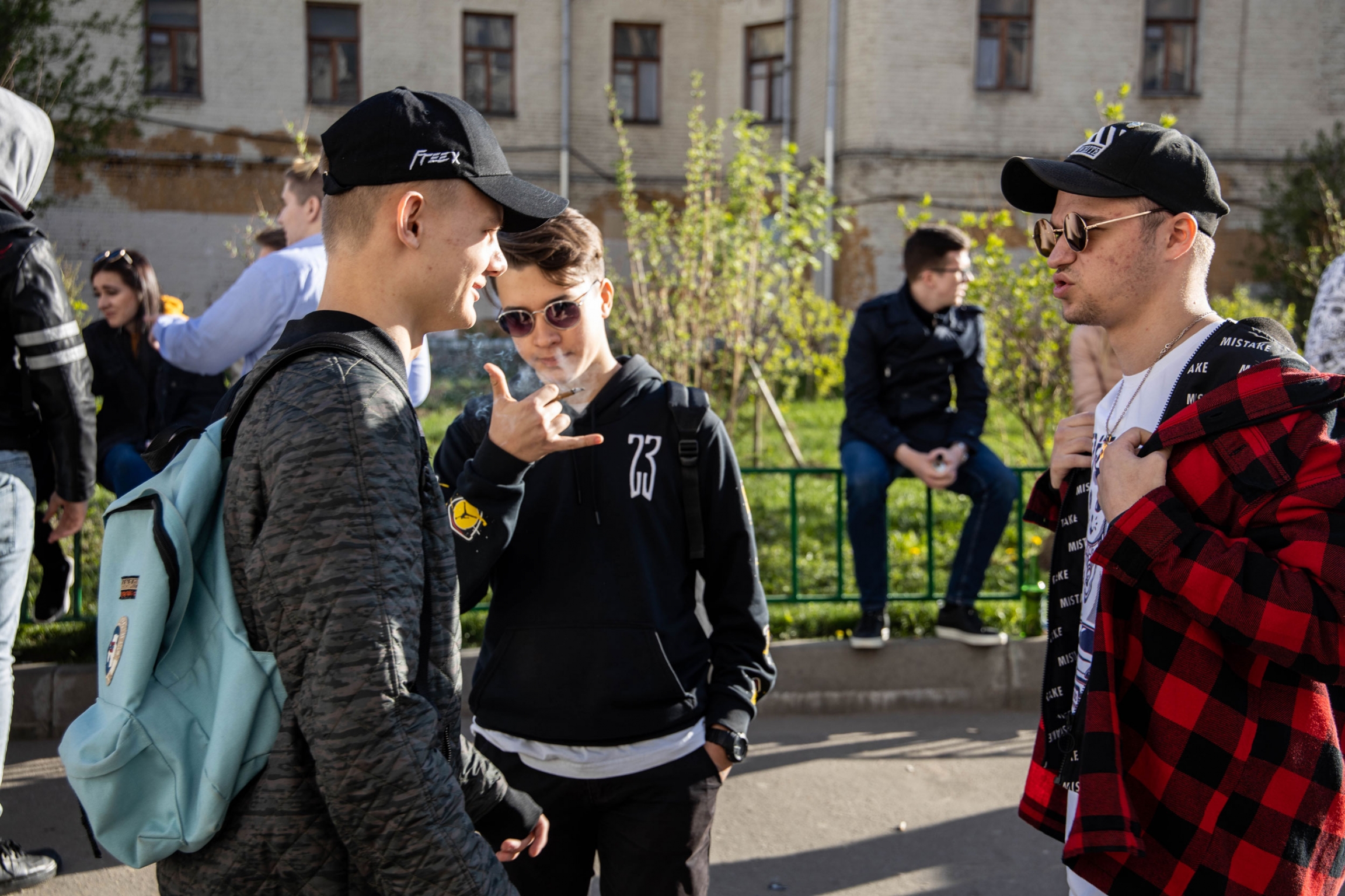 Several people wait outside the Alibi Club before the night’s rap battle. Two Men talk outside while one smokes in Russia.