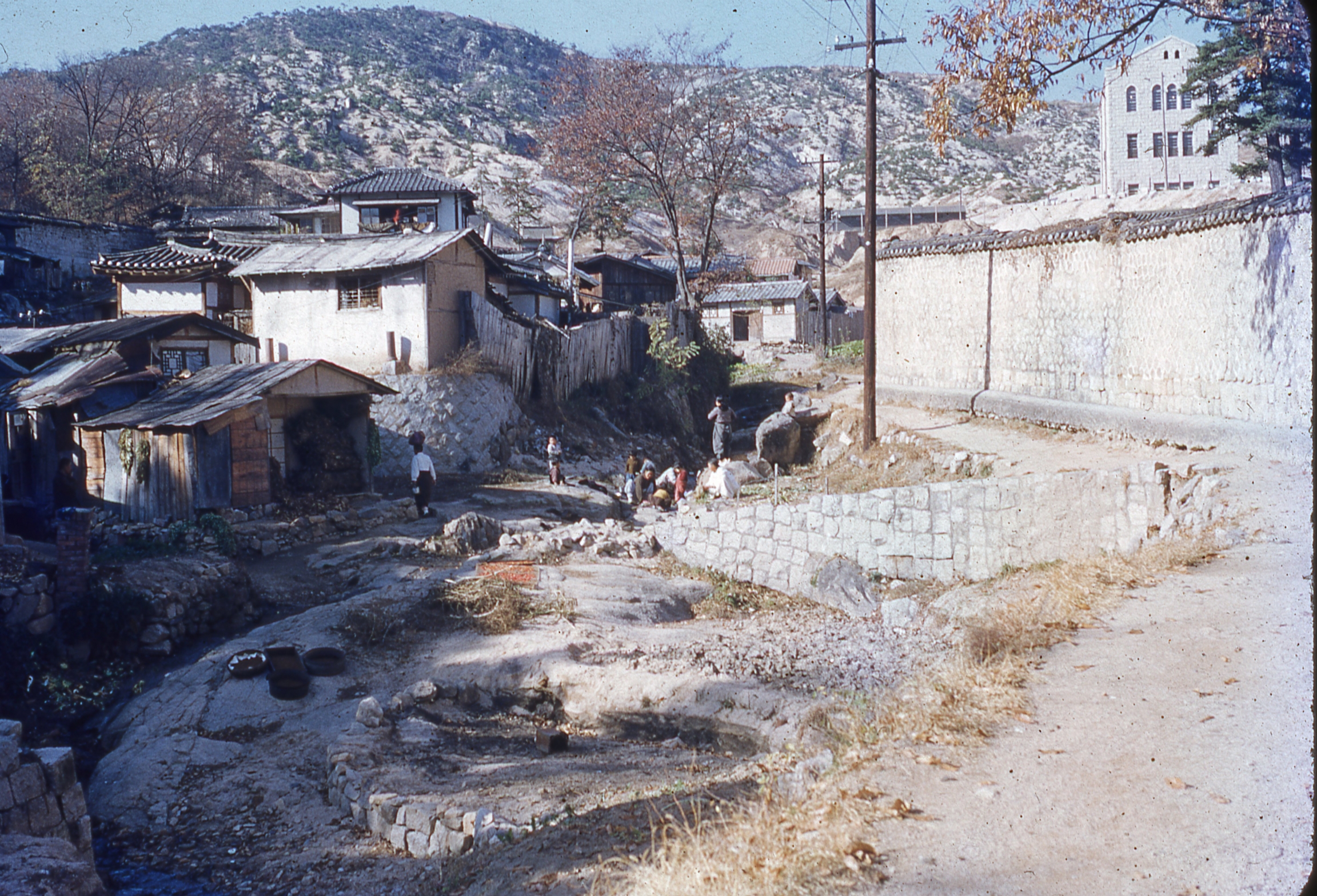 washing clothes in a stream near huts
