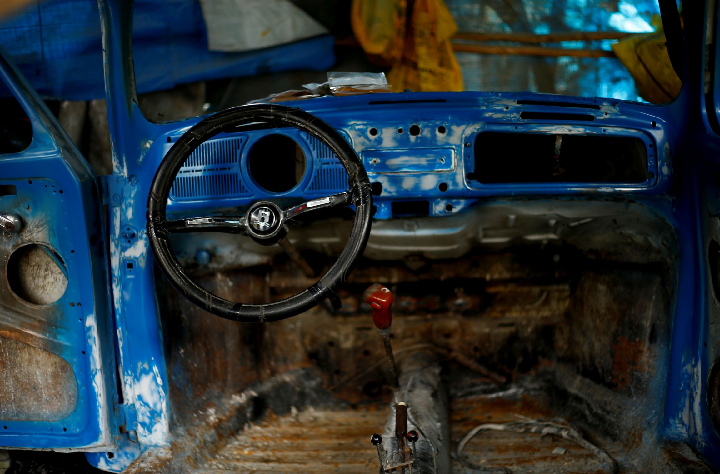 The interior of a Volkswagen Beetle car is seen at a garage in Addis Ababa, Ethiopia. The blue, stripped down interior of a Volkswagen Beetle car is shown along with a black steering wheel.