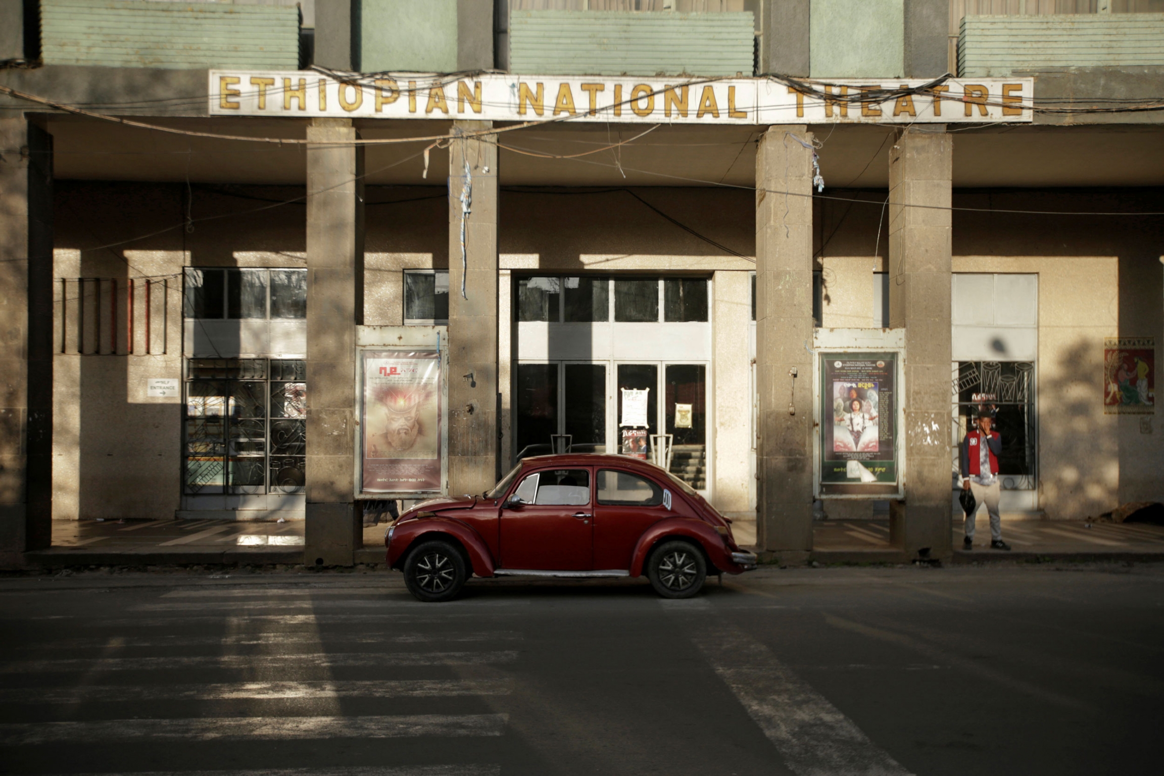 A 1978 model Volkswagen Beetle is parked in front of the Ethiopian National Theatre in Addis Ababa, Ethiopia. A red Volkswagen Beetle is show parked in front of the tall columns of the Ethiopian National Theatre.