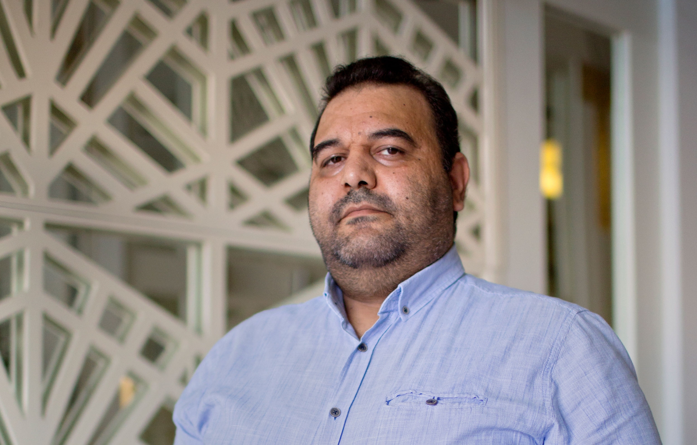 Mouath Youssef is an activist from Syria. A man is shown looking at the camera and wearing a blue, button-down shirt.