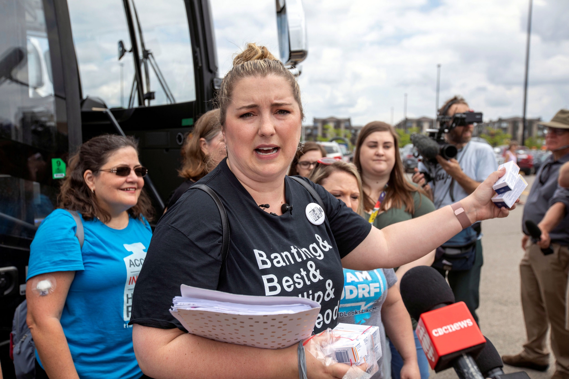 A woman and diabetes Type 1 patient speaks with the media standing next to a bus