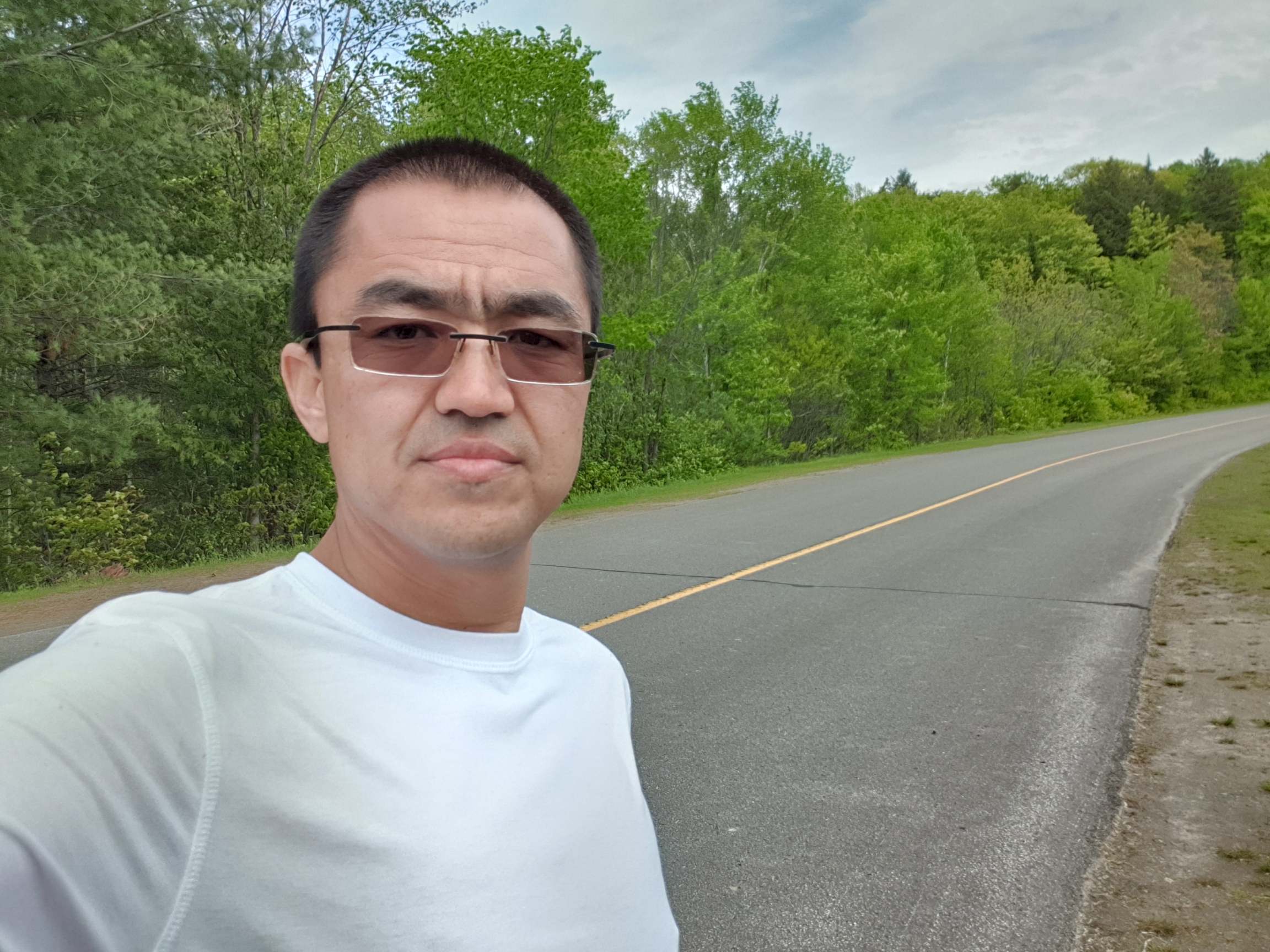 A man wears a white shirt and sunglasses outdoors