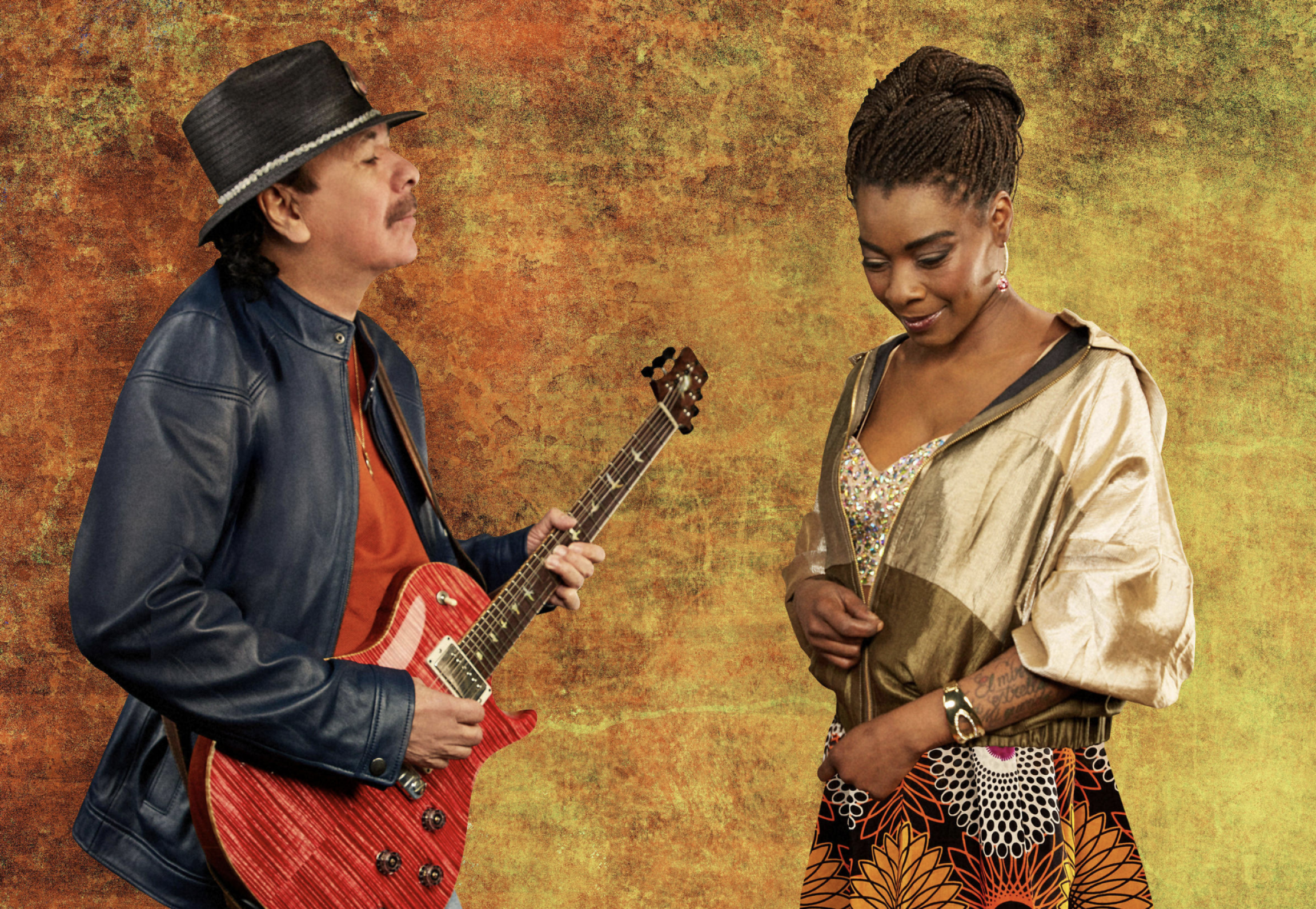 Carlos Santana and singer Buika. A man plays the guitar in front of a woman looking down to the floor.