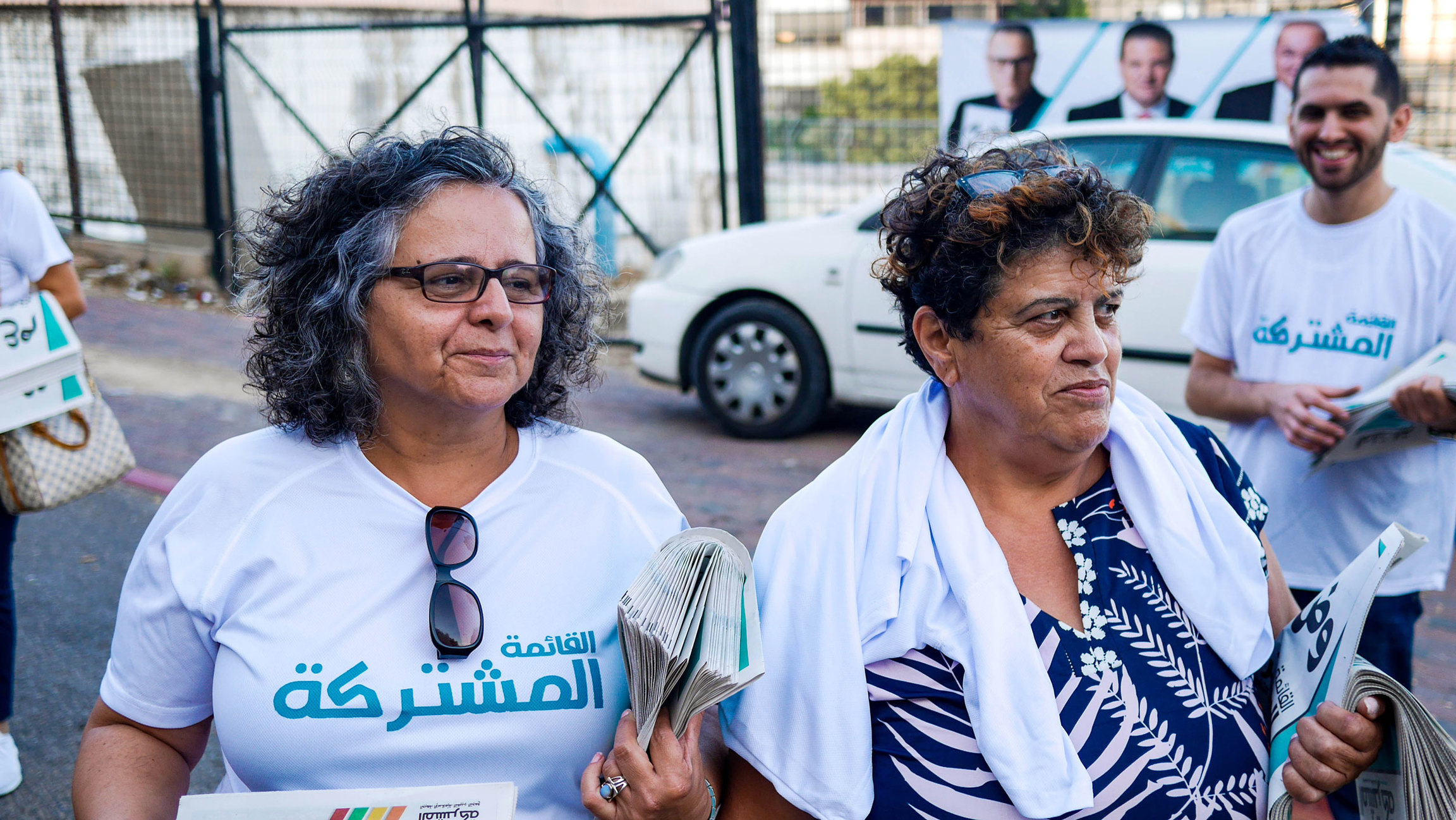 Aida Touma-Sliman (left) from the Joint Arab List running in Tuesday's election, handing out campaign information in Nazareth with a party activist, Nabila Istanbuli. Two women are shown standing next to each other, both carrying newspapers under their arms.