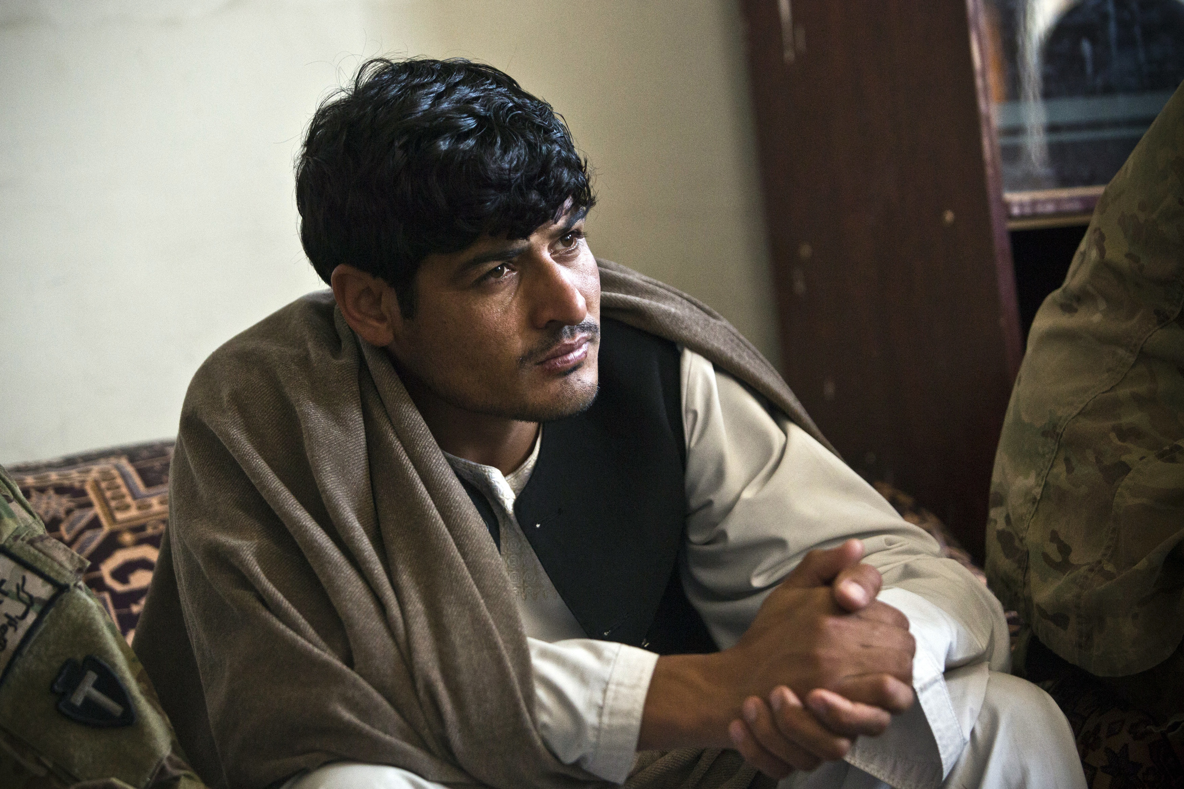A young man wearing a beige hat listens intently