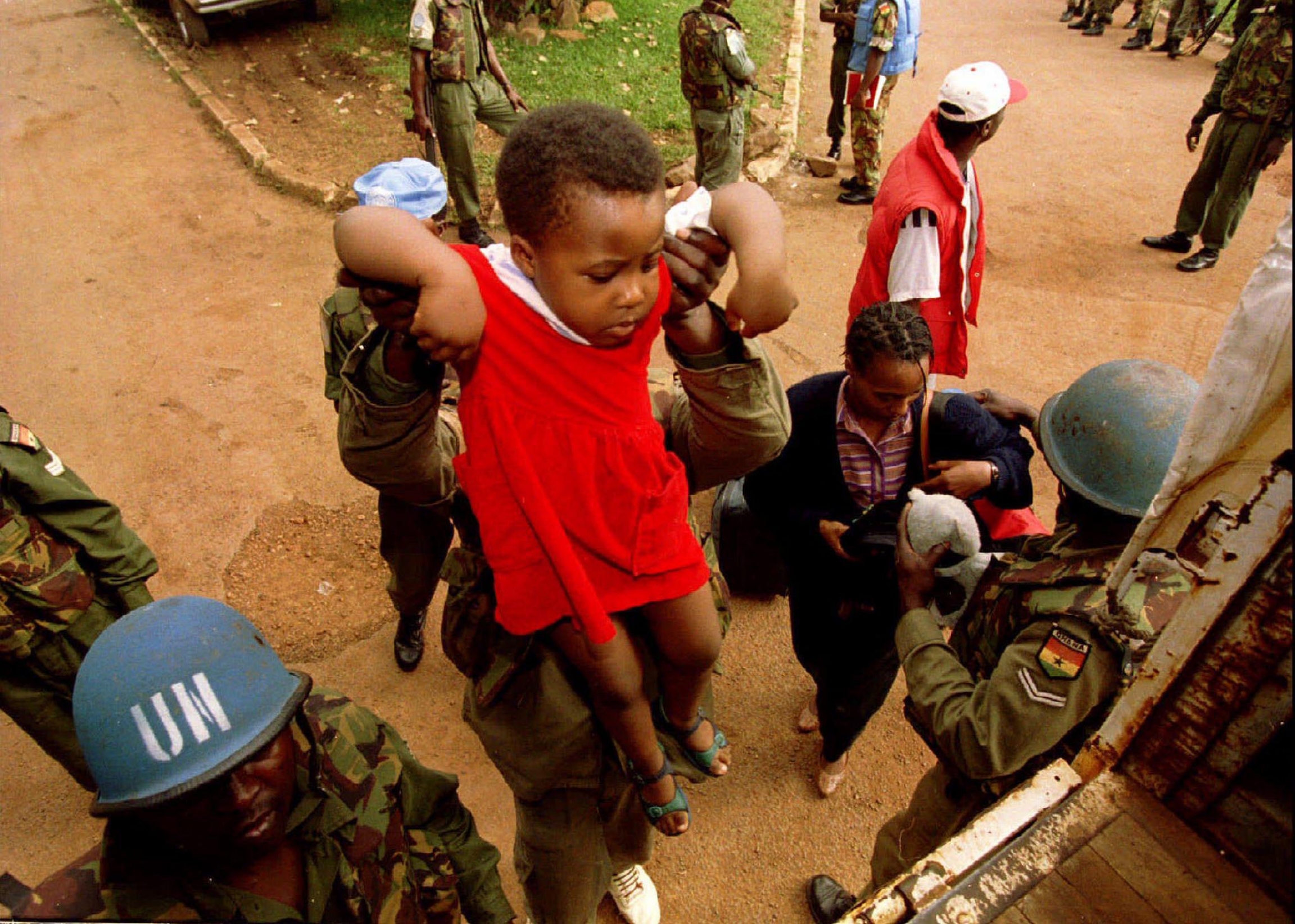 UN peacekeepers transferring a child to a UN ‘safe area’ from a government-held area of Kigali, Rwanda, May 27, 1994. UN peacekeepers hold up a child.
