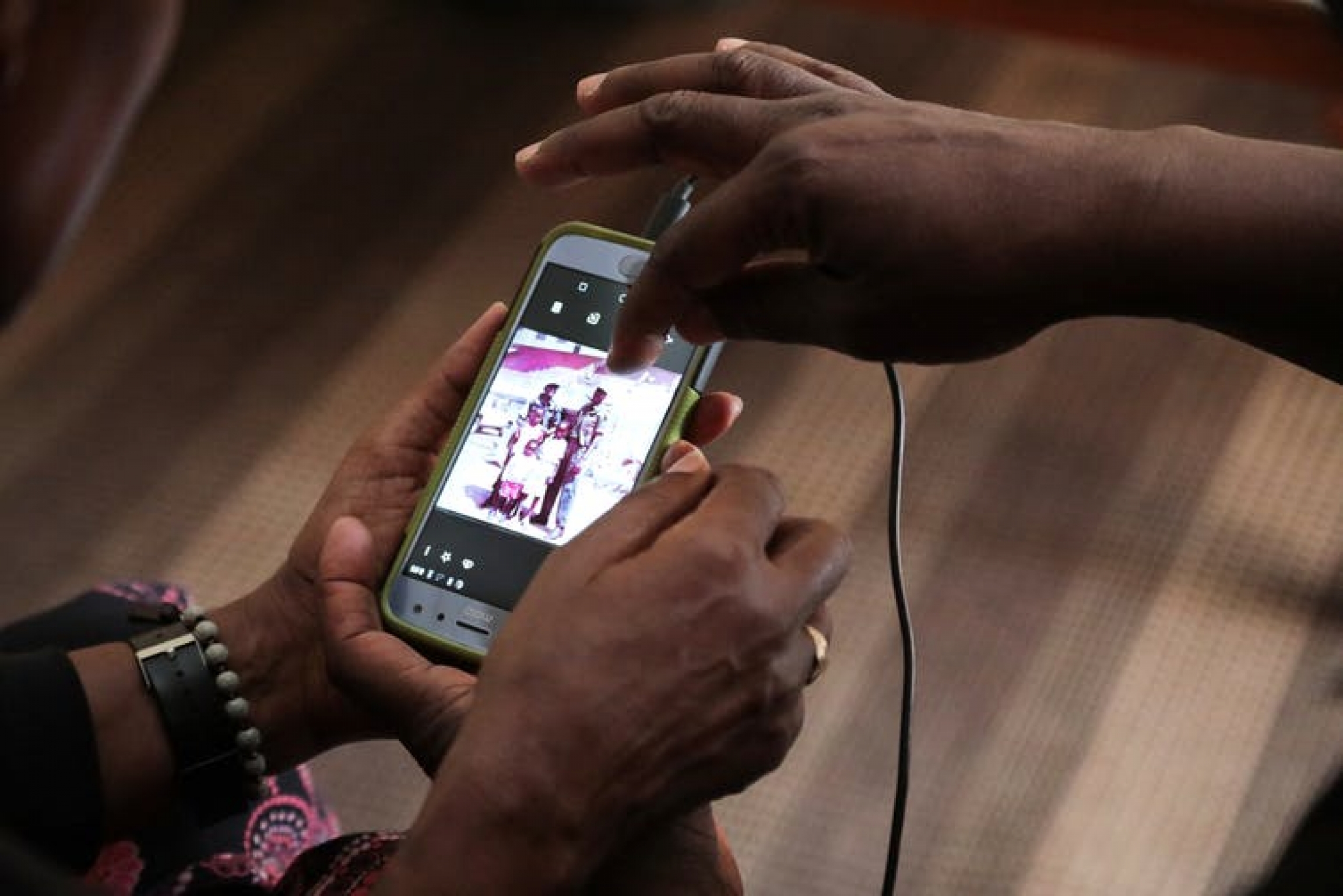 Sosi shows a picture of himself back in 1994 with some Tutsi children he protected through the Rwandan genocide. A man holds a phone with a picture of himself.