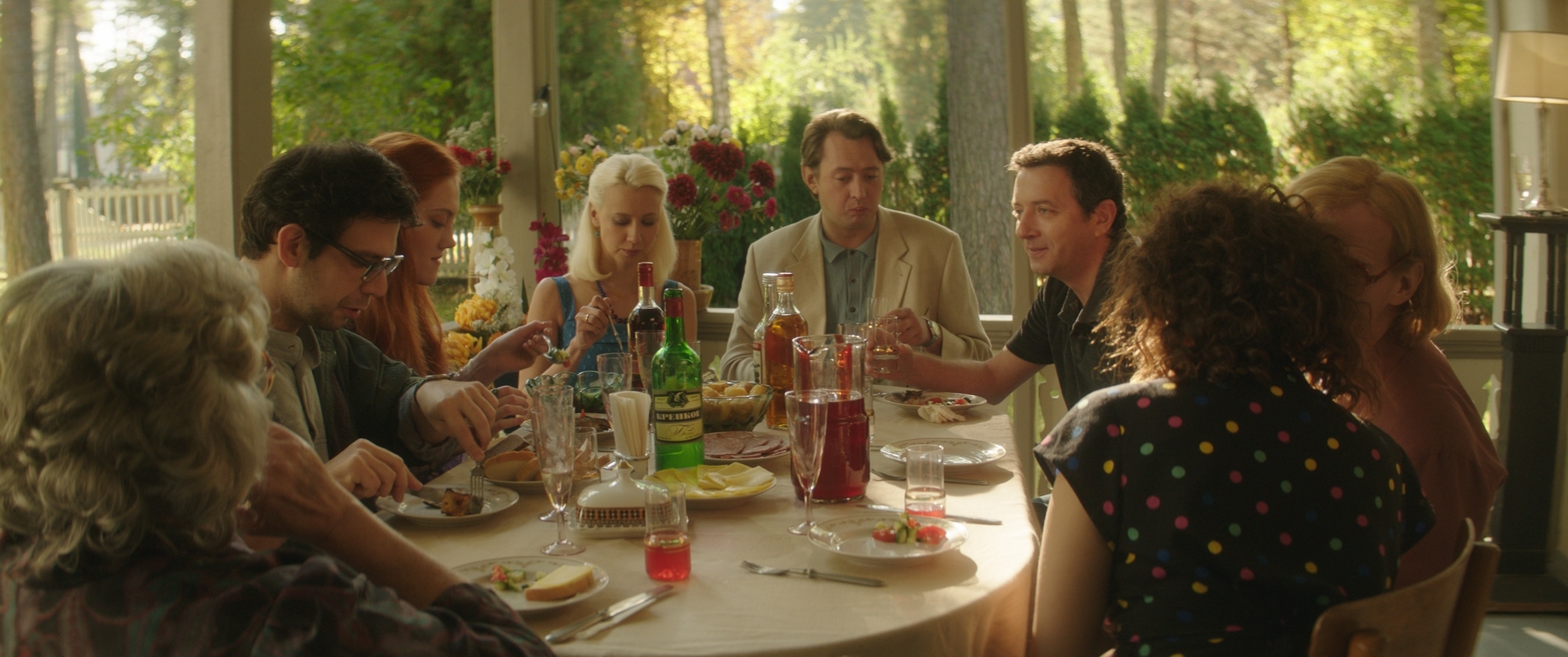 Still from "The Humorist" A sepia-toned film still of people sitting around a table.