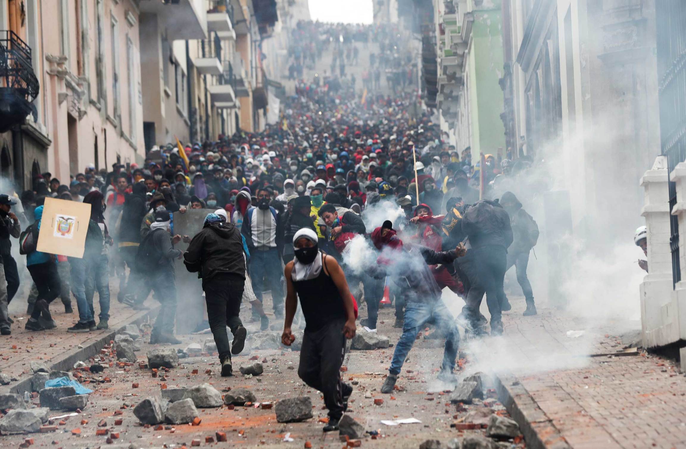 Protestors fill a city street as smoke from tear gas hangs in the air