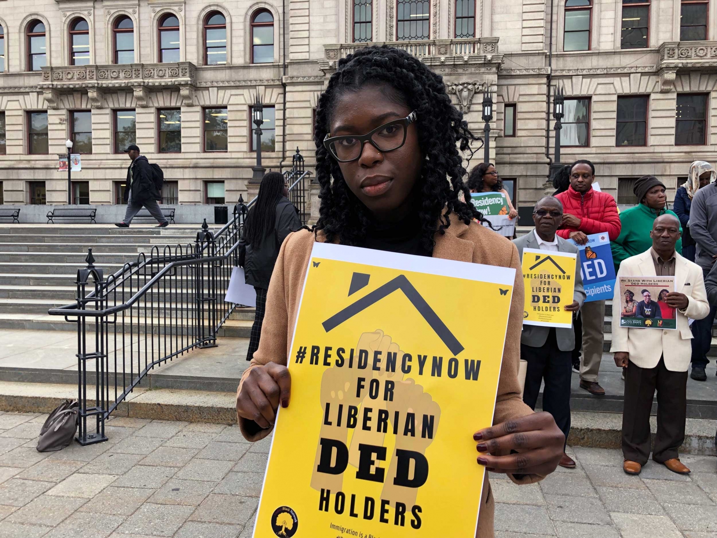 Yatta Kiazolu, a 28-year-old PhD candidate at the University of California, Los Angeles, said she could face deportation in March due to the Trump administration's termination of a legal program that allows her and other Liberians to stay in the US. A woman holds a sign that reads, "Residency now for Liberian DED holders."
