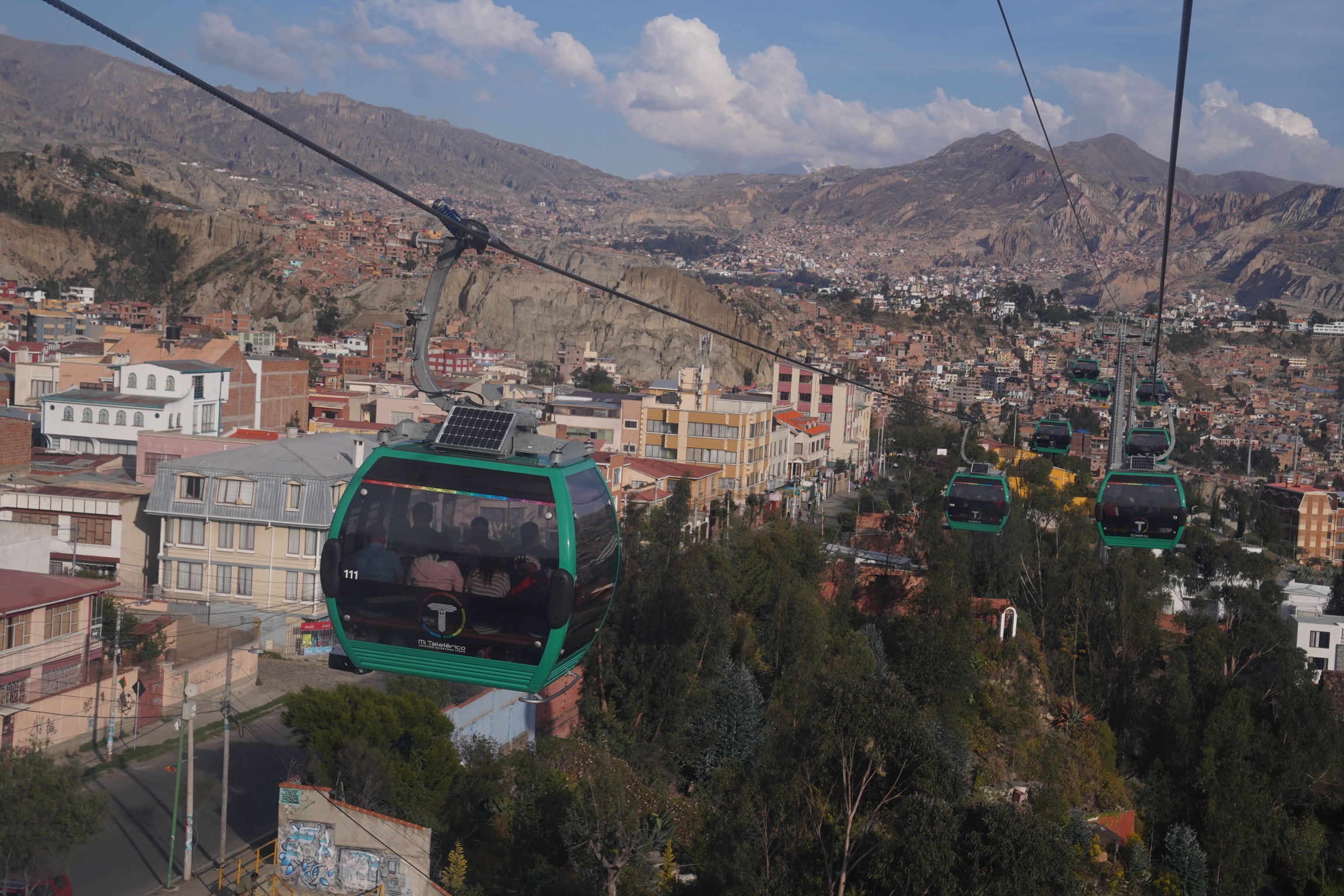 Evo Morales has won the support of many Bolivians by investing into public infrastructure projects like this cable car system that connects the capital city. Early in his tenure, he renegotiated contracts with gas and mining companies to bring more money A cityscape with cable car system with views of the mountains in the background