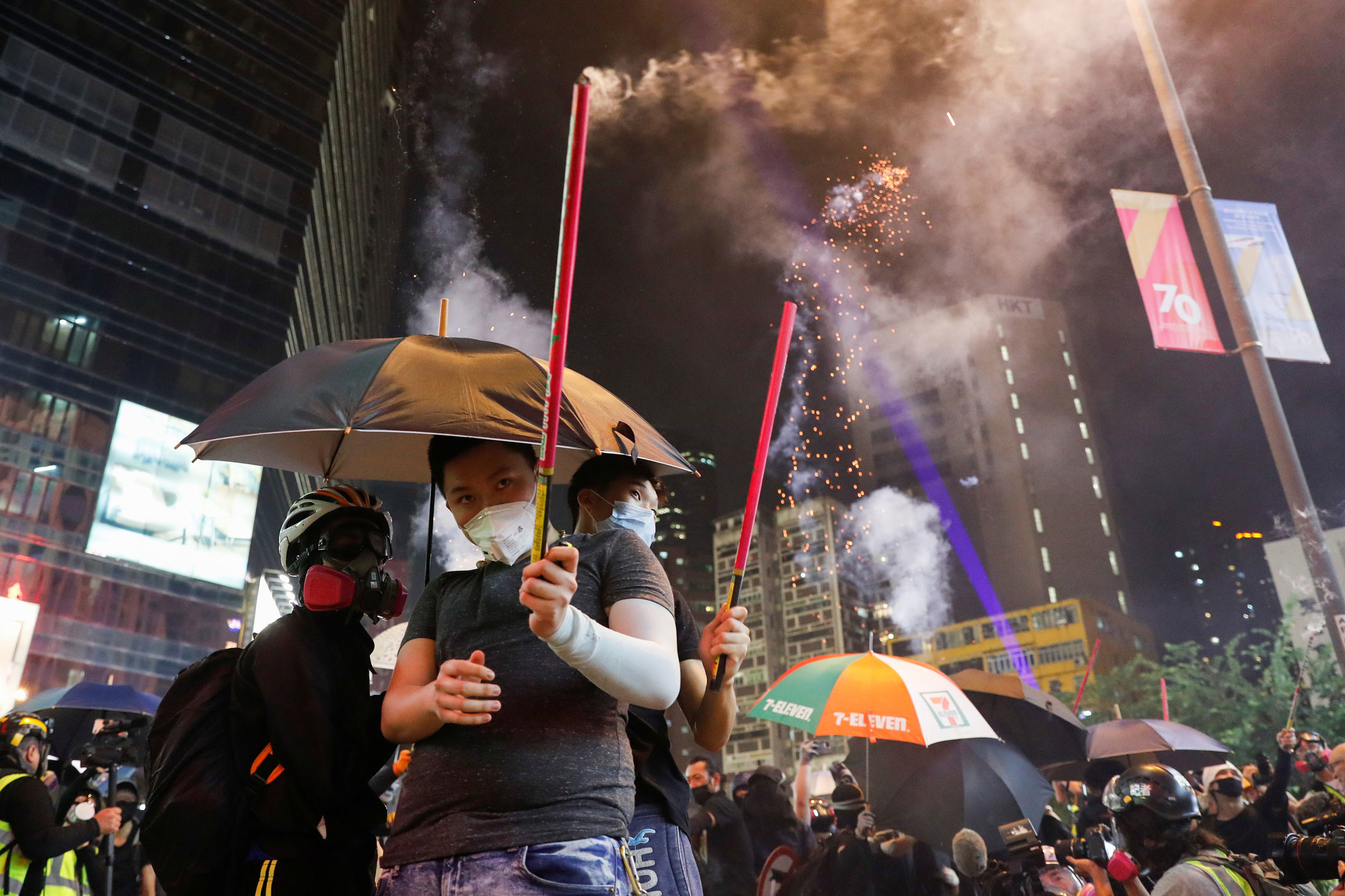Anti-government protesters release fireworks during a demonstration on China's National Day. A group of protesters are shown with umbrellas and holding fireworks.