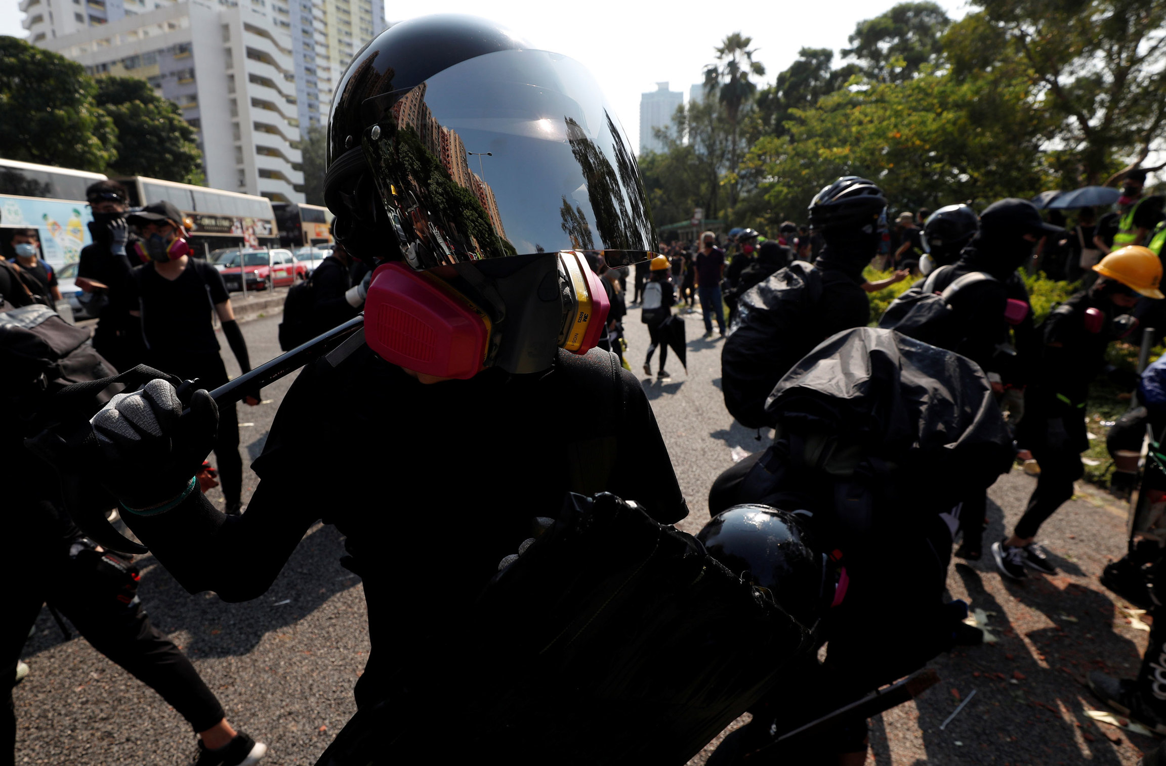 An anti-government protester walks in Sha Tin district, on China's National Day. A protester is shown wearing a helmet with a reflective face shield and a pink gas mask.