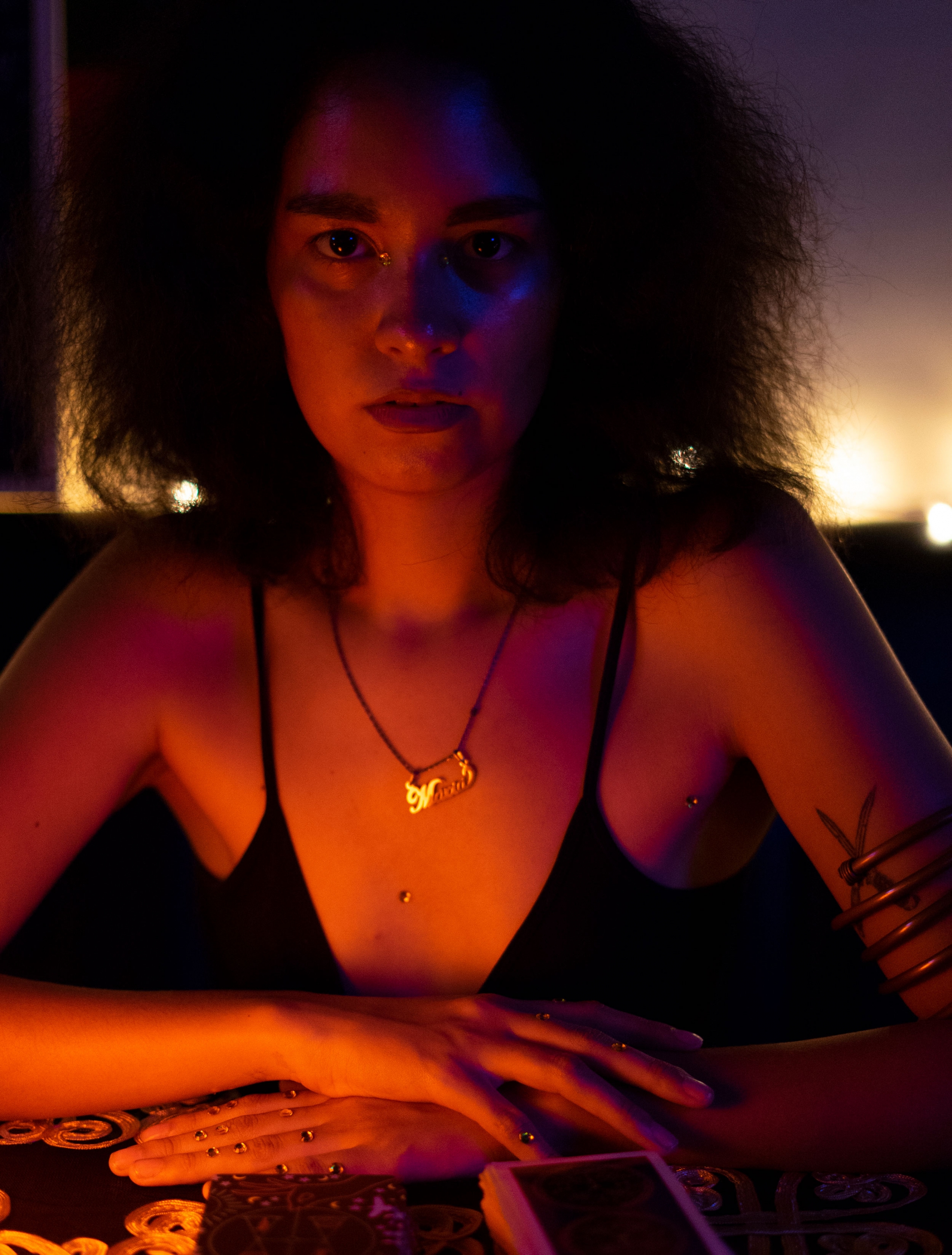 Maria Manrique says she's an aspiring wise woman who treats the physical through herbal magic and reads Tarot to heal mind and spirit. Maria Manrique is shown in a close-up portrait with gemstones in the creases of her eyes.
