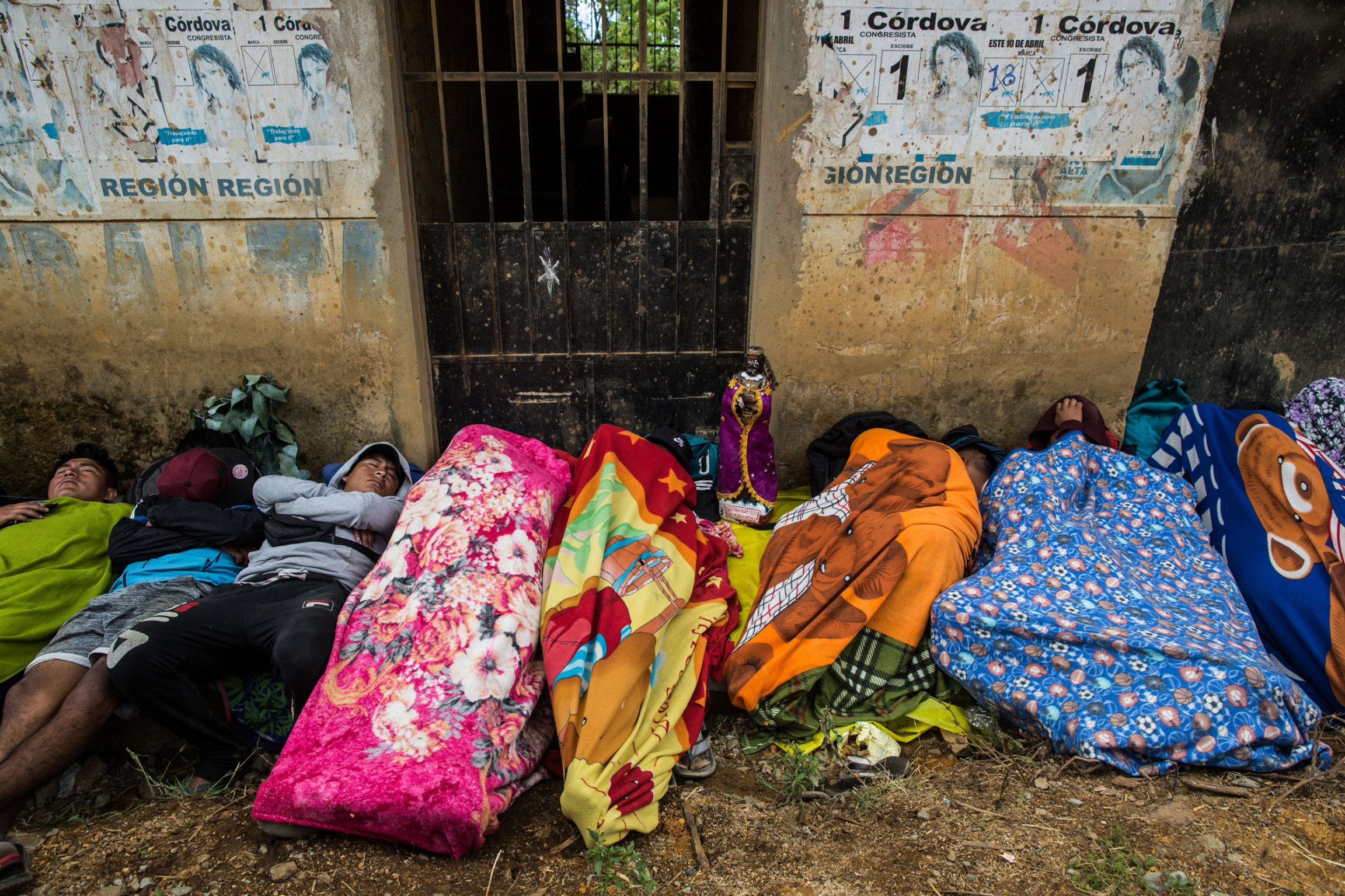 Pilgrims rest on the road on their way to Ayabaca. There are devotees who walk for days, weeks or even months — some pilgrims walk more than 1,000 miles to reach Ayabaca in October. Pilgrims are shown wrapped in colorful blankets laying on the ground on the side of the road.