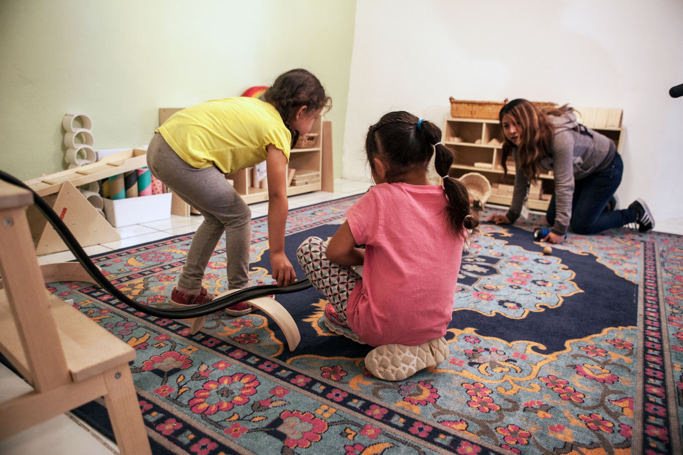 Children play at the Nest. Two young girls are shown playing with a toy racing track.