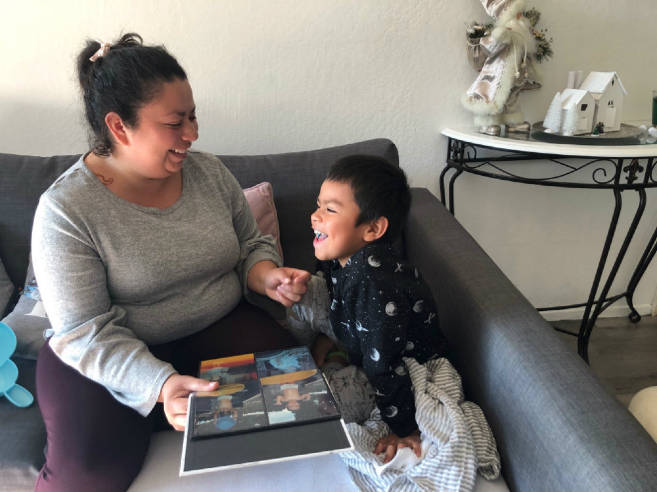 A woman sits with her child, looking at an album.