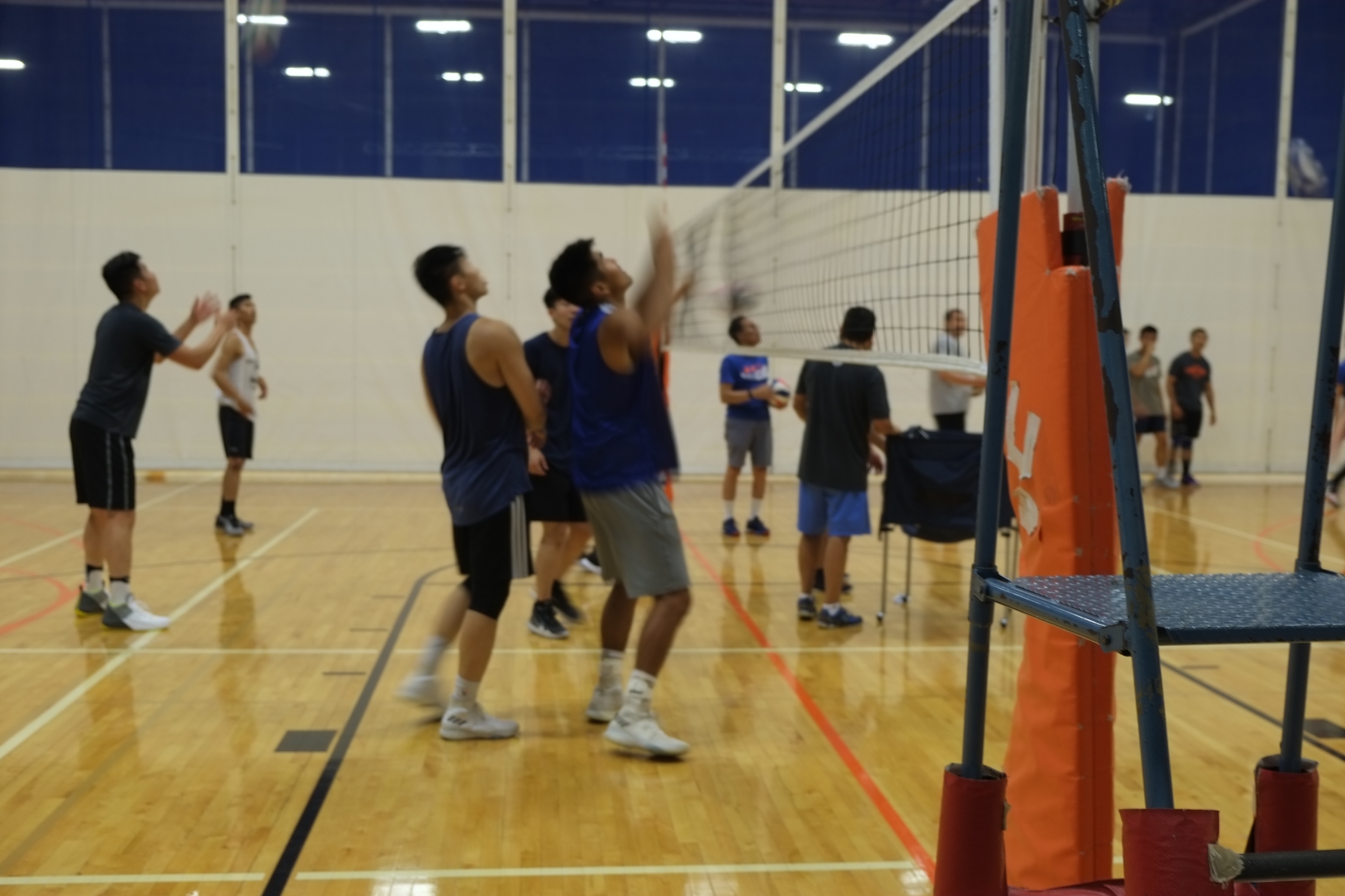 One of the Boston Hurricane’s top 9-man teams practices on a Thursday evening in a gym complex at Newton South High School, Newton, Massachusetts, on July 25, 2019. Asian men play a volleyball game in uniforms on a court