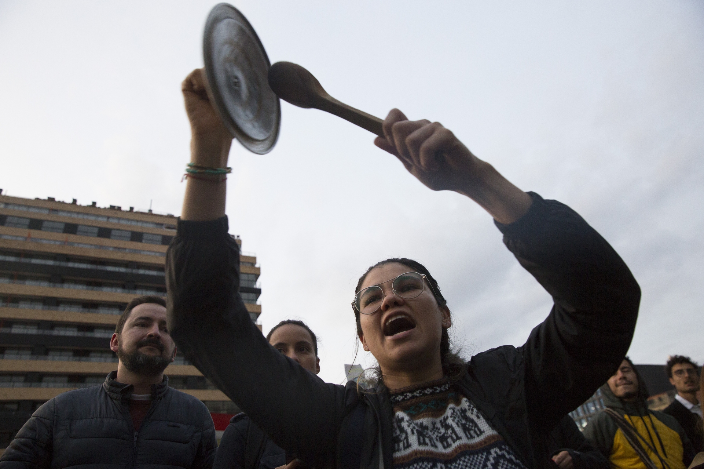 A protester bang pots in a cacerolazo in Bogotá, Colombia, to protest the country's government on Nov. 22, 2019. A woman bangs on a pot