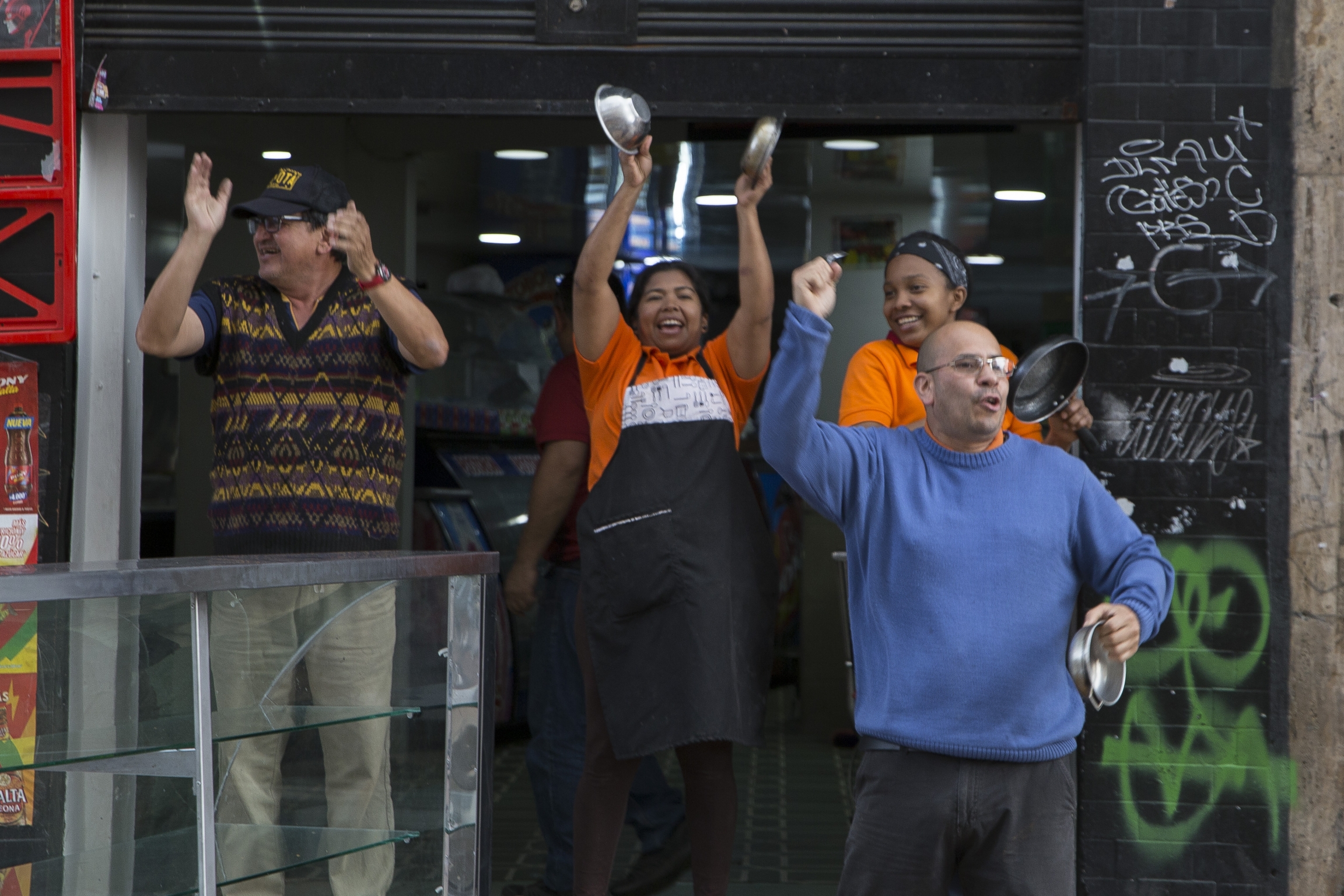 Workers in uniform bang on pots in the street