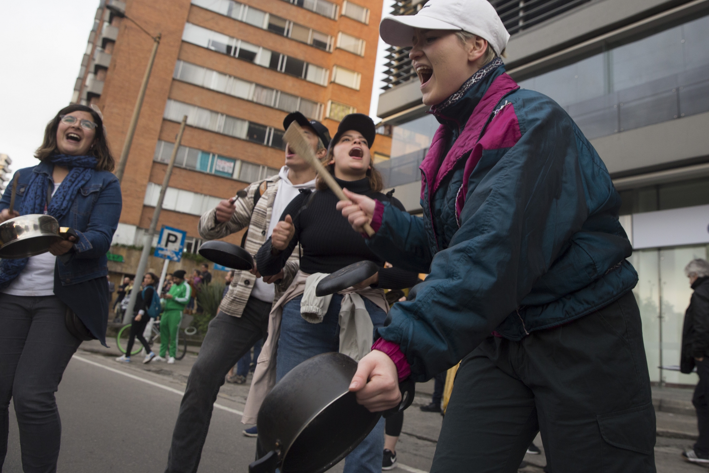 Protesters bang pots in a cacerolazo in Bogotá, Colombia, to protest the country's government on Nov. 22, 2019. Protesters stand in a semi-circle wearing coats and bang on lids and pans