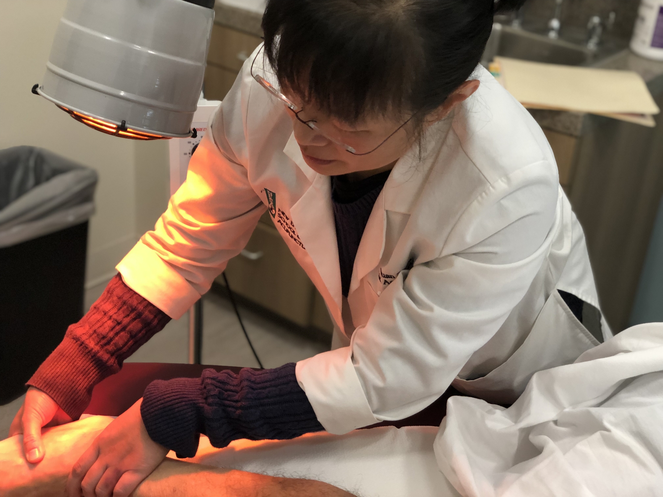 Quan Zhou, a traditional Chinese medicine practitioner, performs acupuncture on a patient's foot at the New England School of Acupuncture, on Nov. 9, 2019. A doctor performs acupuncture on a patient's foot