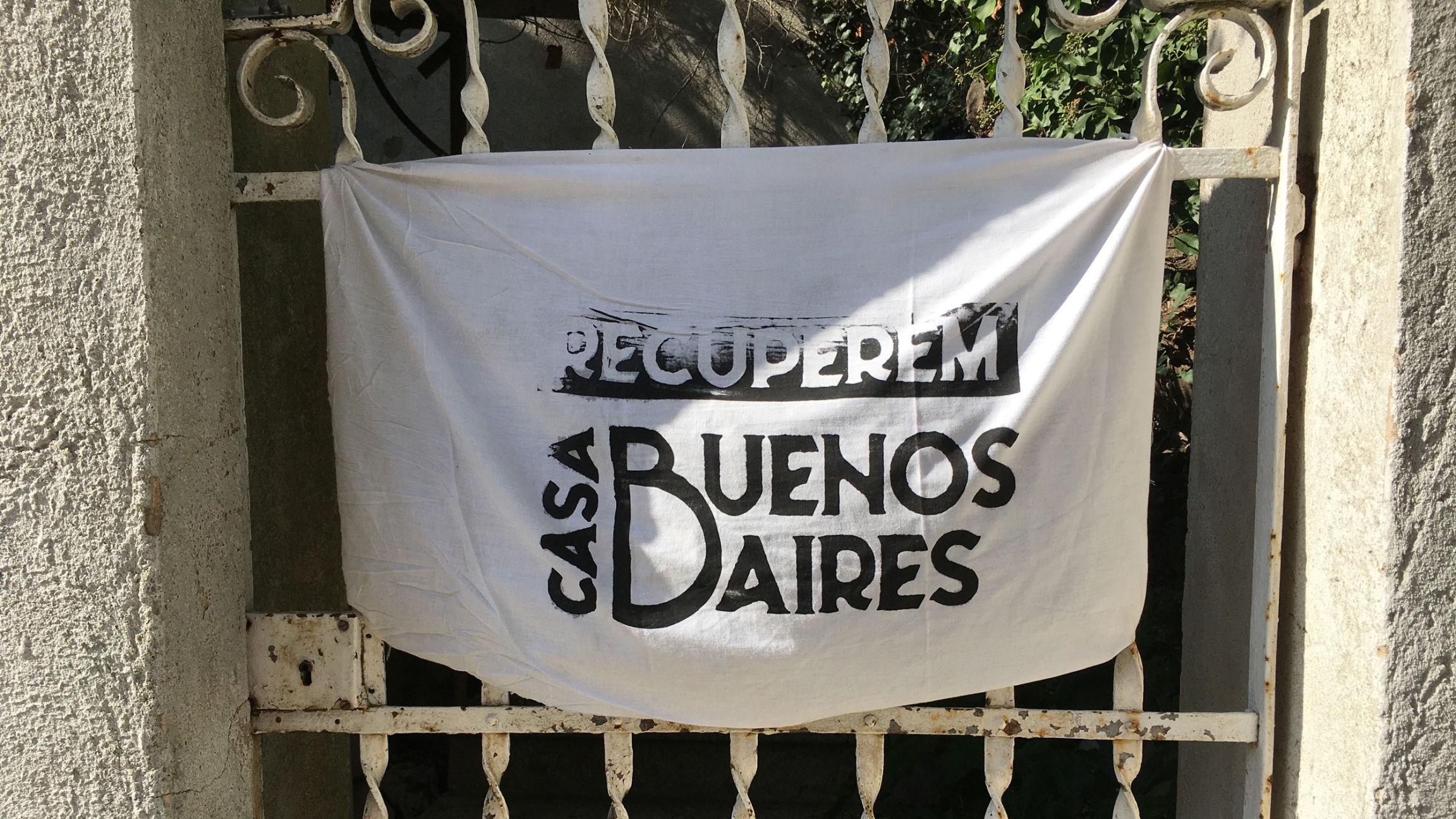 A sign hanging from a private home across from Casa Buenos Aires says in Catalan: "Let's reclaim Casa Buenos Aires." A sign hanging from a private home across from Casa Buenos Aires says in Catalan: "Let's reclaim Casa Buenos Aires."