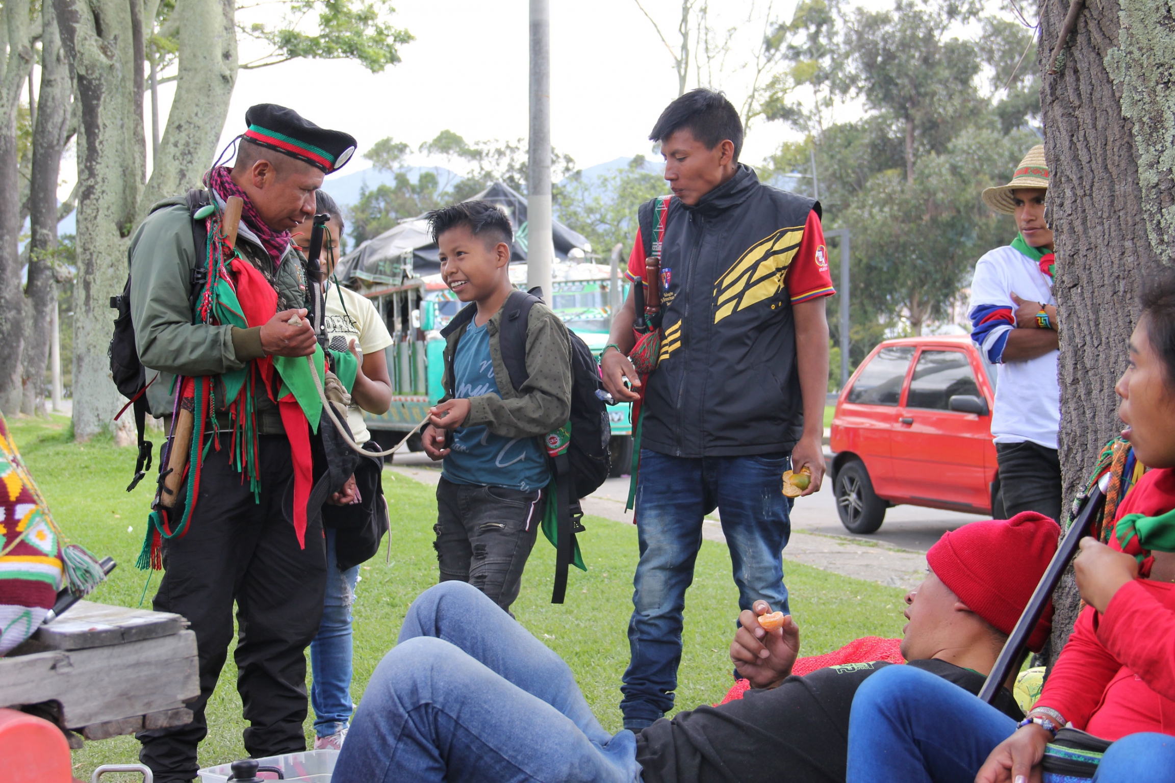 Jose Albeiro Camayo speaks to a young member of the Nasa community on the grounds of Bogota’s National University while other Guards watch on. Jose Albeiro Camayo is shown speaks to two younger men outside on a tree-lined street.