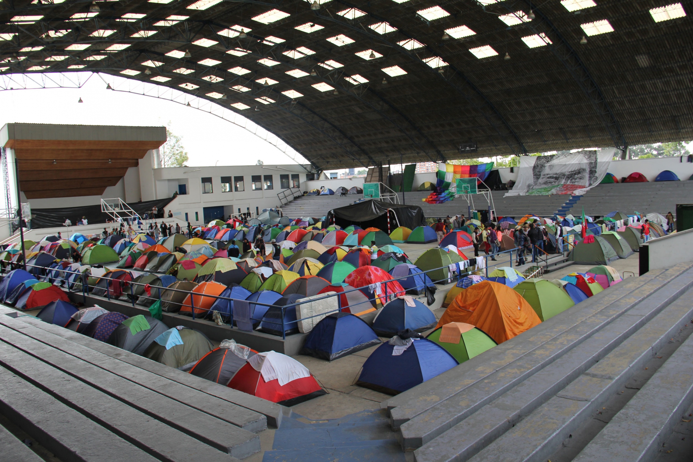 A stadium at Colombia’s National University, where just some of the Indigenous visitors stayed during their visit to attend the National Strike in Bogota. The floor of a stadium is filled with small pup tents.