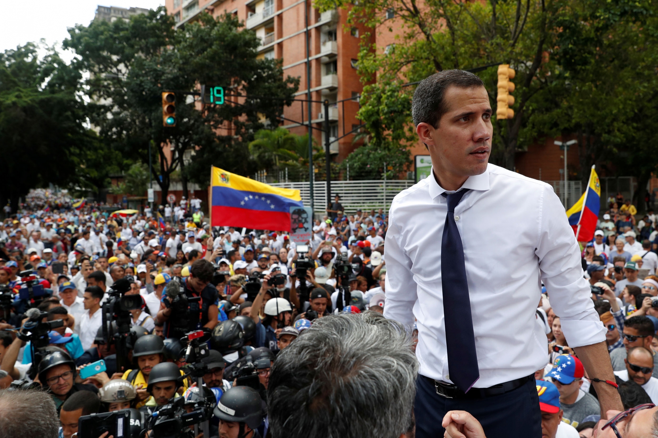Venezuelan opposition leader Juan Guaidó, who many nations have recognized as the country's rightful interim ruler, takes part in a rally against the government of President Nicolás Maduro in Caracas, Venezuela, July 5, 2019. Venezuelan opposition leader Juan Guaidó is shown wearing a white shirt and tie in front of a large group of people.