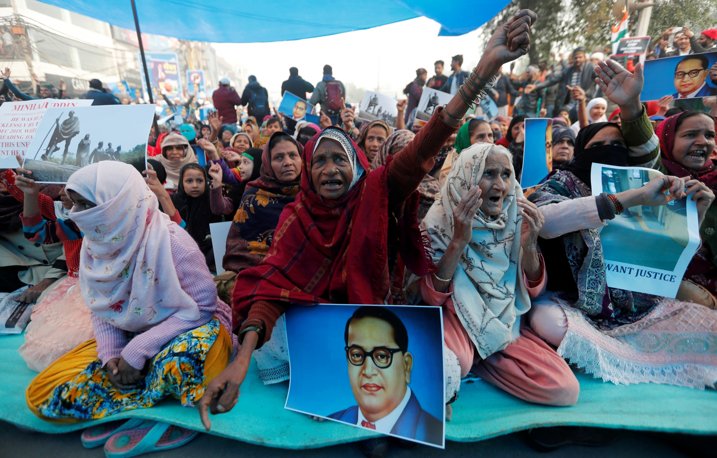 Demonstrators shout slogans during a protest against a new citizenship law in Delhi, India, Dec. 20, 2019. Women wearing sarees protest with signs in Delhi while sitting down