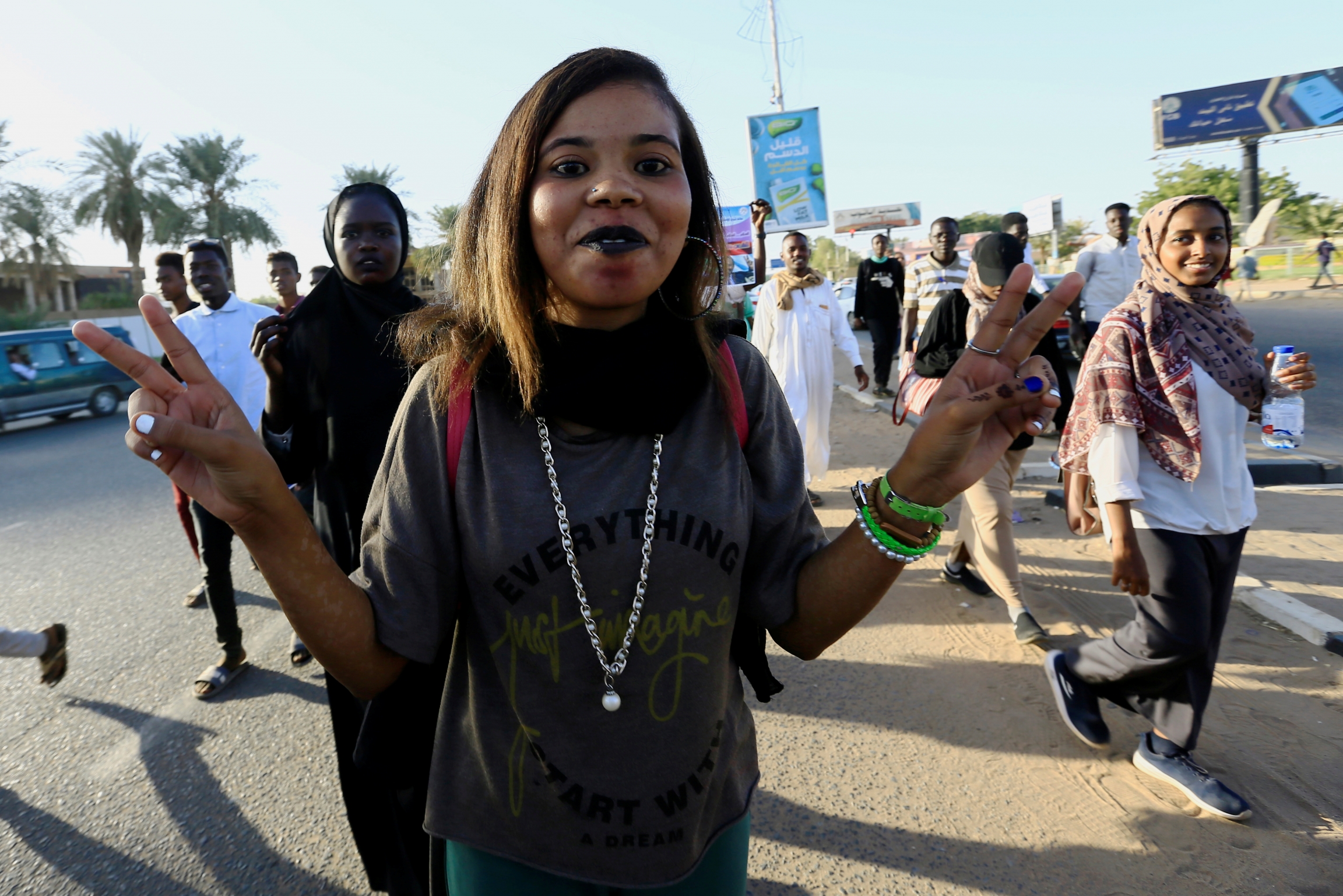A Sudanese woman flashes a victory sign as people gather during the first anniversary of the start of the uprising that toppled long-time ruler Omar al-Bashir. A woman flashes a peace sign with a smile
