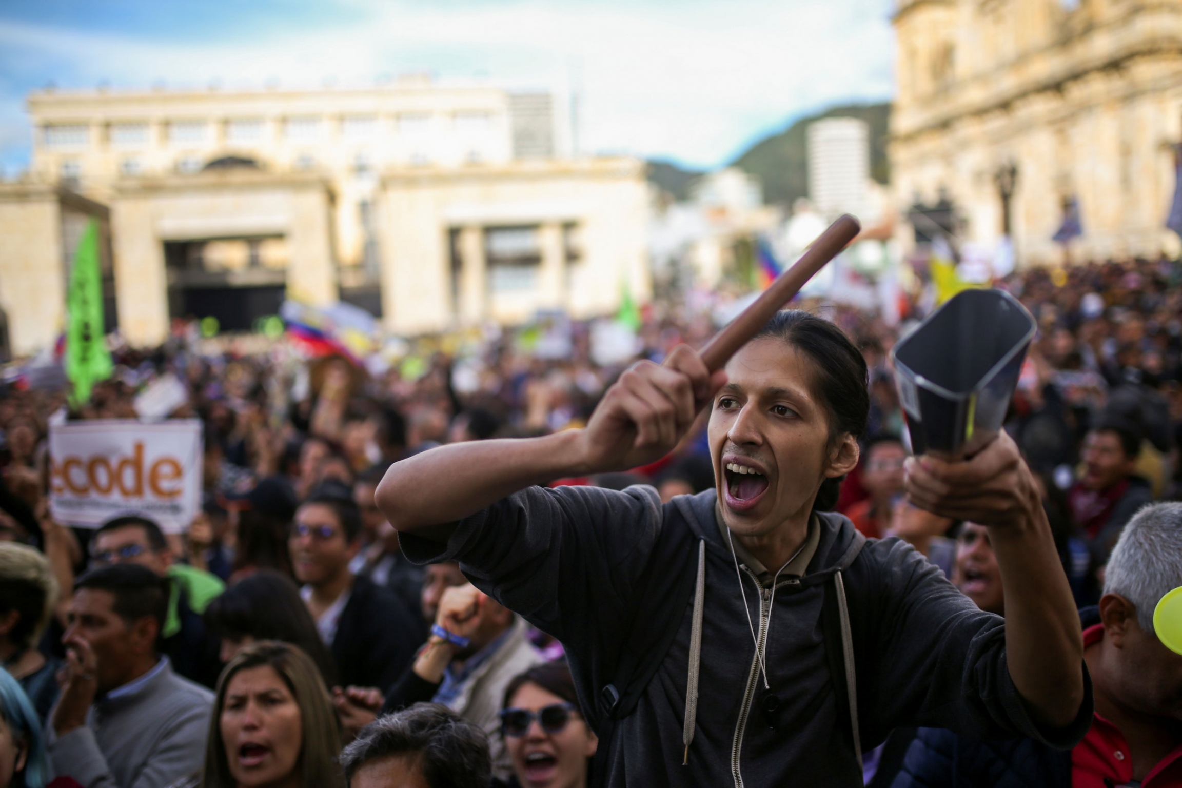 A demonstrator takes part in a protest as a national strike continues in Bogota, Colombia, Dec. 16, 2019. A large group of protesters are shown with a person in the nearground holding a cowbell.