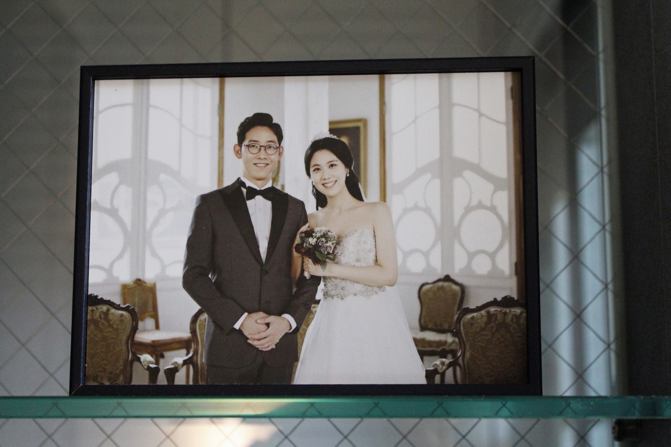 A wedding photo of Cho Sung-won and Seo Ji-hye rests on a shelf by their apartment entryway. A wedding photo of a Korean couple