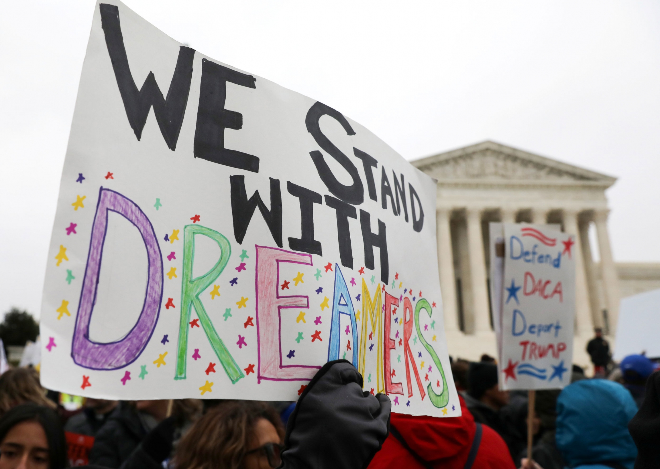Demonstrators rally outside the US Supreme Court as justices were scheduled to hear oral arguments in the consolidation of three cases before the court regarding the Trump administration's bid to end the DACA program A group of demonstrators are standing an carrying signs with one that has, "We stand with Dreamers" printed on it.