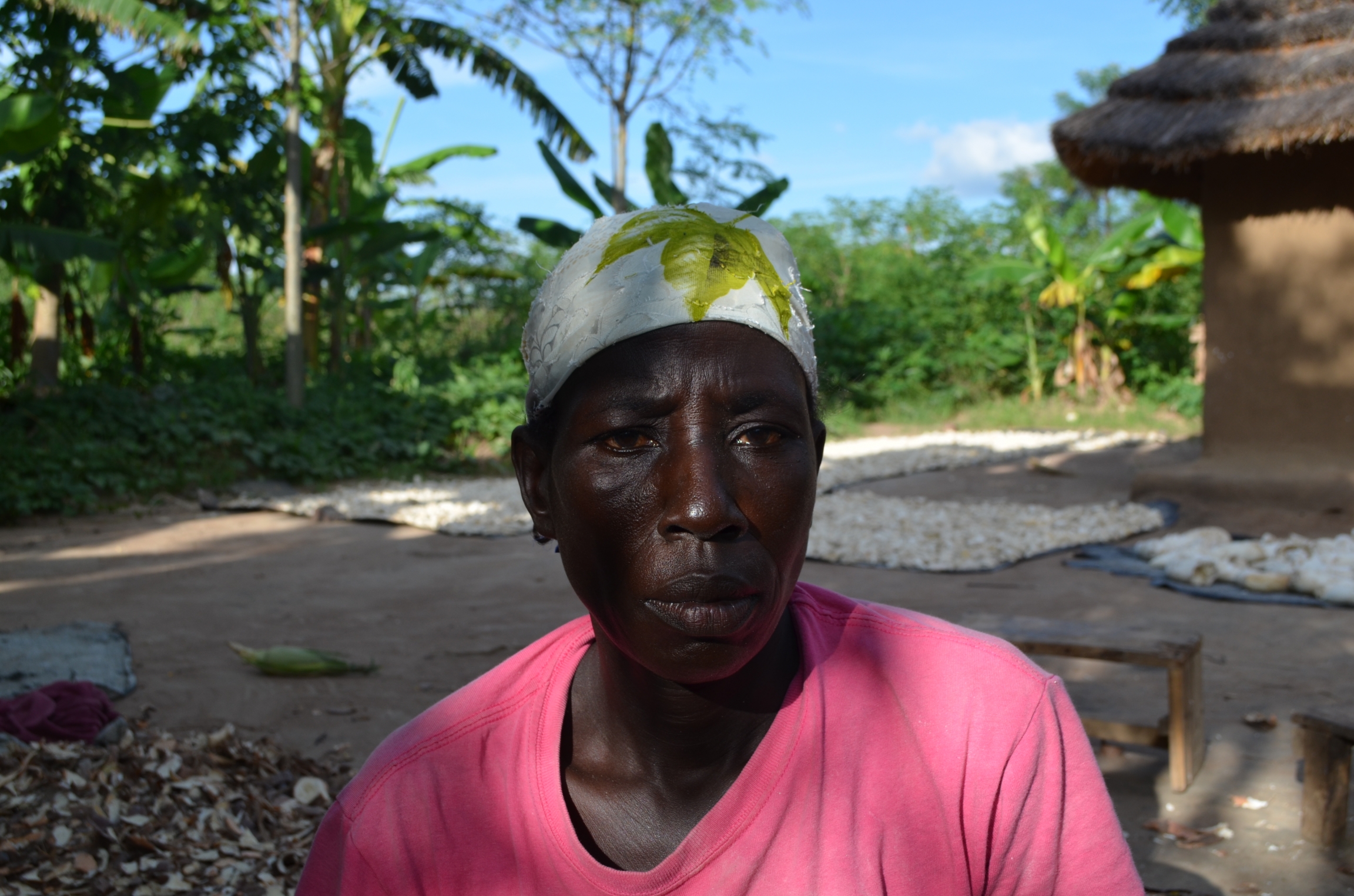 Margaret Nyakato, a 50-year-old widow and mother of eight, says her family was pressured into signing an unfair compensation deal, Nov. 30, 2019, Bulisa district, Uganda. A woman wears a pink shirt and a head wrap.