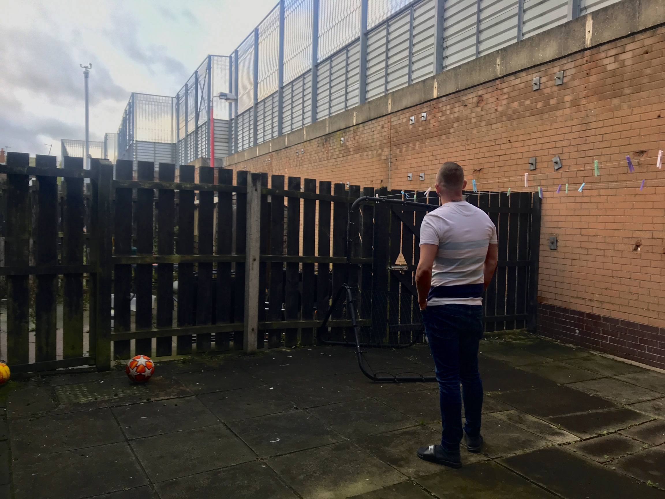 Un uomo in piedi con le spalle alla telecamera di fronte al muro della pace
