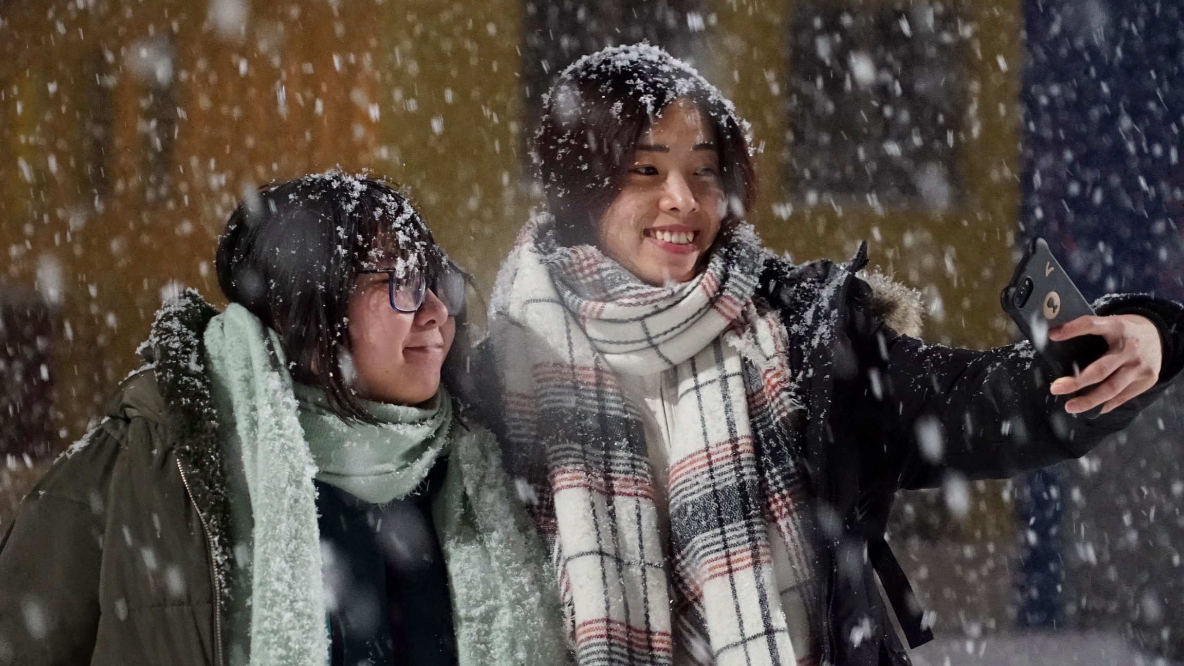 Tourists from China take a selfie in Teriberka, Russia. Tourists from China take a selfie as large snow flakes are falling all around them.