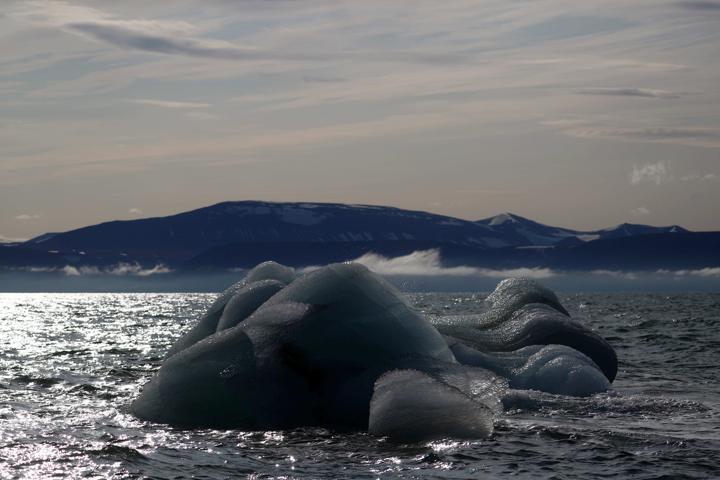 An iceberg floats near the Wahlenberg Glacier in Oscar II land at Spitsbergen in Svalbard, Norway, Aug. 5, 2019. Ice melts in a body of shimmering water
