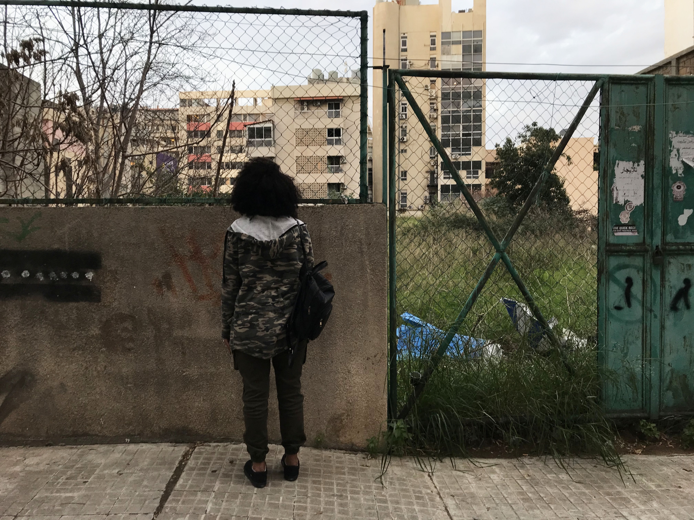 Tsigereda stands in front of a row of apartment buildings near the Migrant Community Center in the Hamra neighborhood of Beirut, where activists with the Anti-Racism Movement help provide resources and classes for migrant workers. A young woman stands outside looking out at apartment buildings
