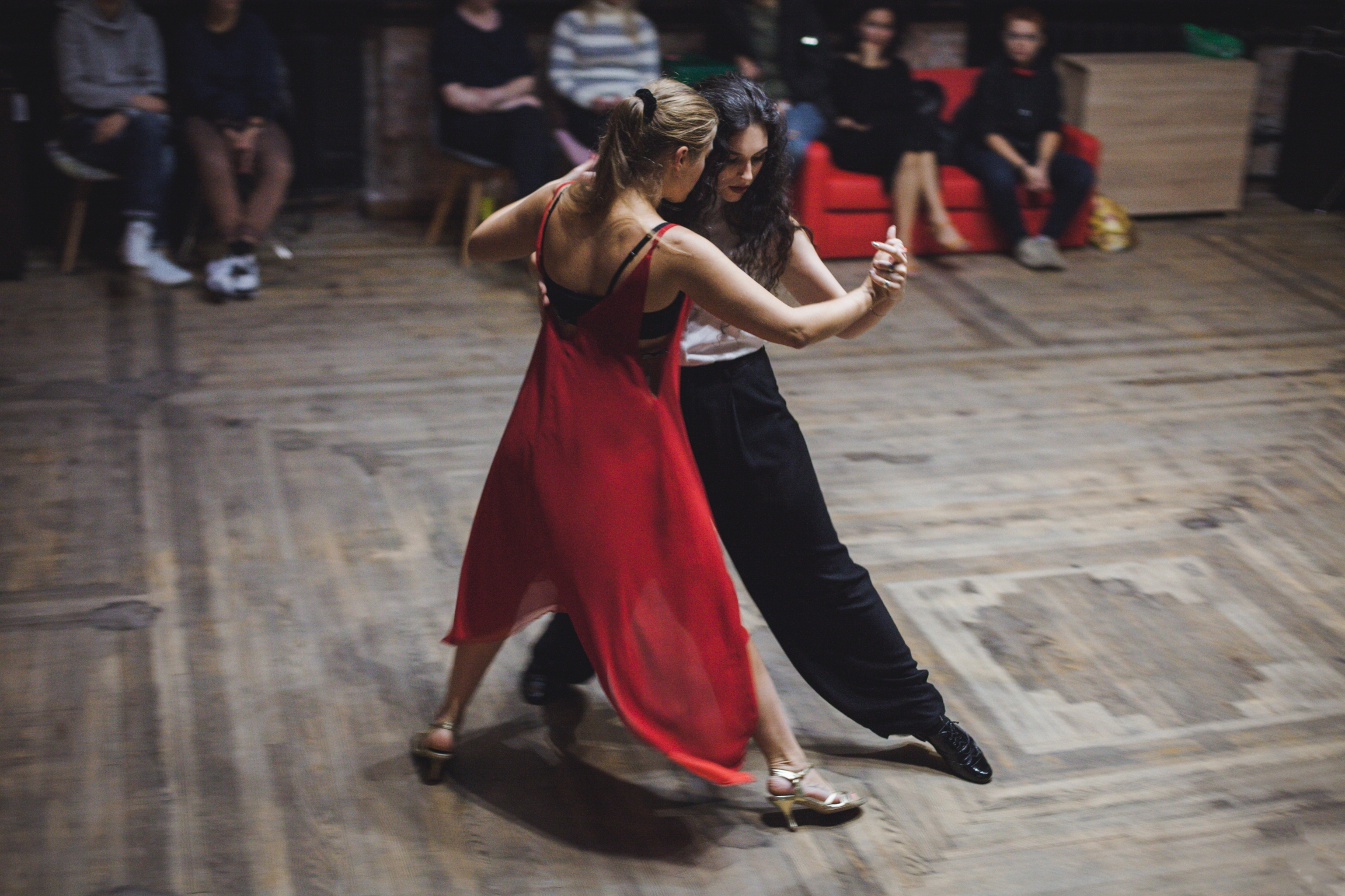 Organizer Marina Ventarron (right) with dance partner and instructor Anna Morisot. A woman in red dances with a woman in black at a dance studio