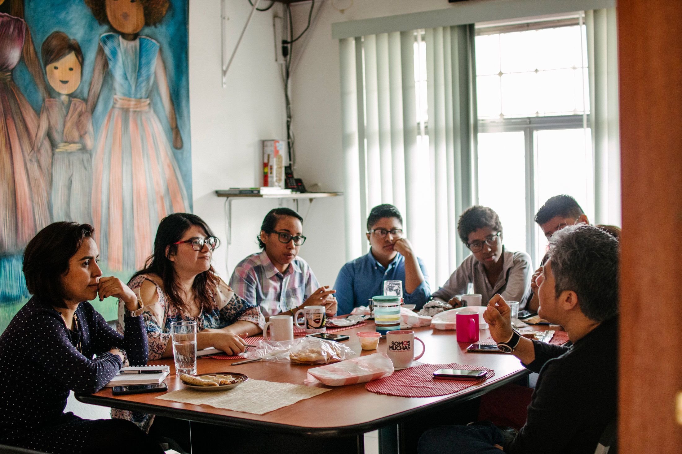 Indyra Mendoza (R), leads a morning meeting at the Cattrachas offices in Tegucigalpa, Honduras. Several people are shown sitting around a table eating breakfast and holding a meeting.