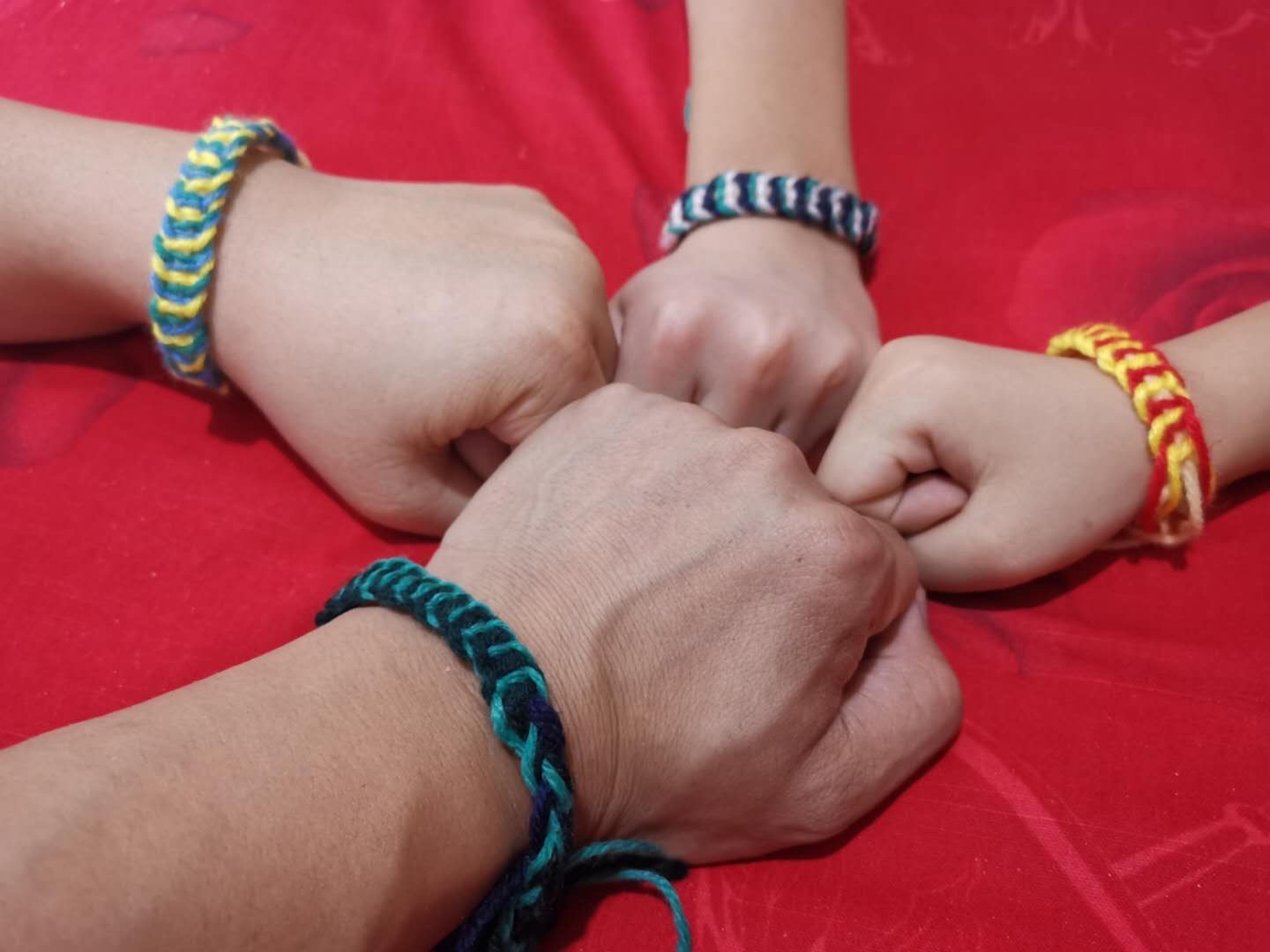 The daughter, Francine, made bracelets for the family during six weeks in lockdown mode in Lanzhou, China. Four arms fist bump to show off their bracelets on their wrists.