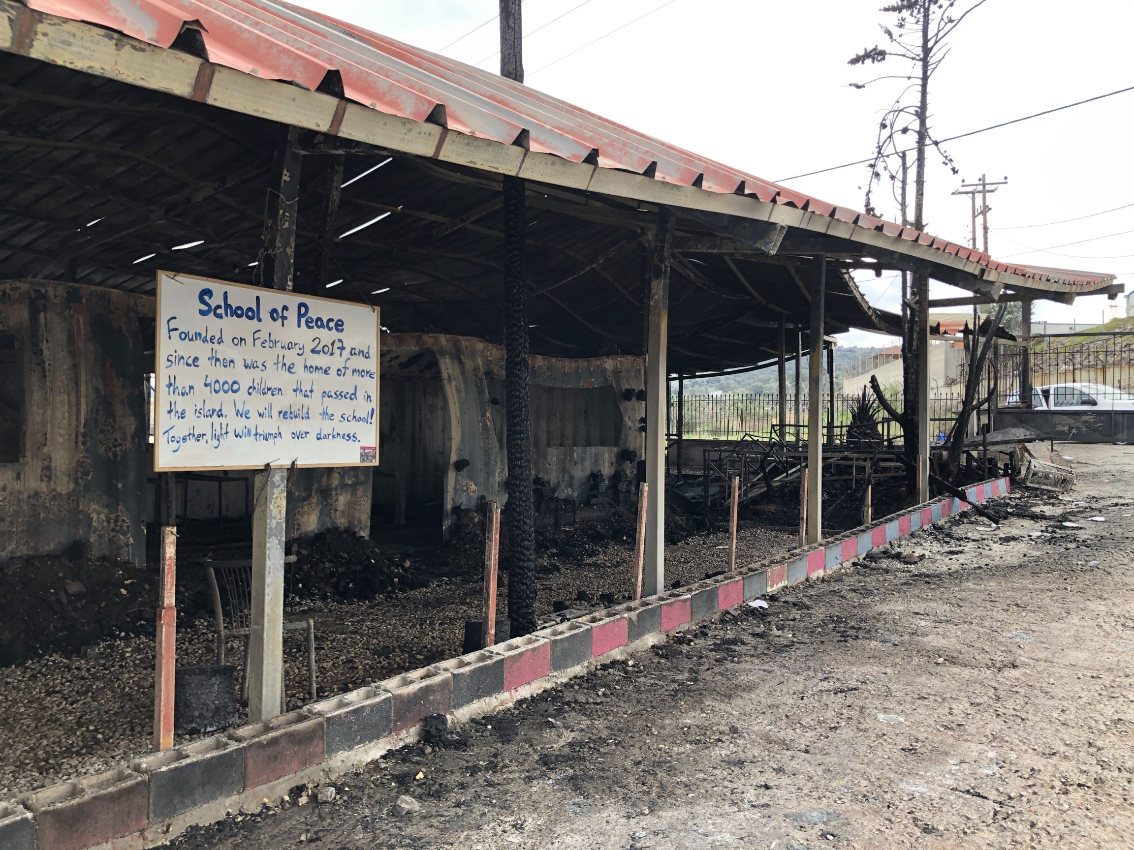 A sign in front of the rubble of the School of Peace